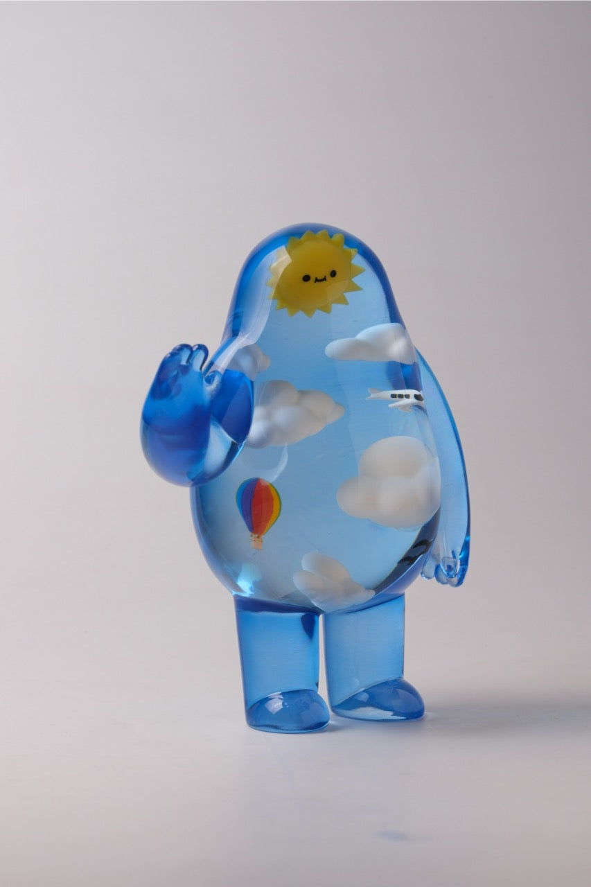 Sky Guy by Sad Salesman, a translucent blue figurine with a whimsical sky scene inside, featuring clouds, sun, hot-air balloon, and airplane.