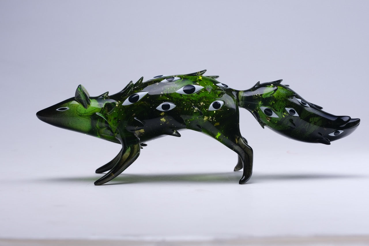 Bogwalker Oracle by Faunwood: A stylized, translucent green glass fox figure with darker flecks and black-and-white eye motifs, mid-stride, 10cm resin, limited edition.