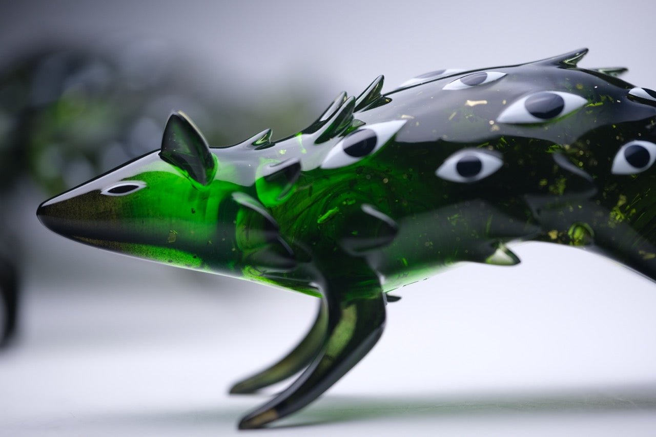 Bogwalker Oracle by Faunwood, a unique 10cm translucent green glass sculpture with eye motifs, limited to 100 pieces, featuring a fish-like form.