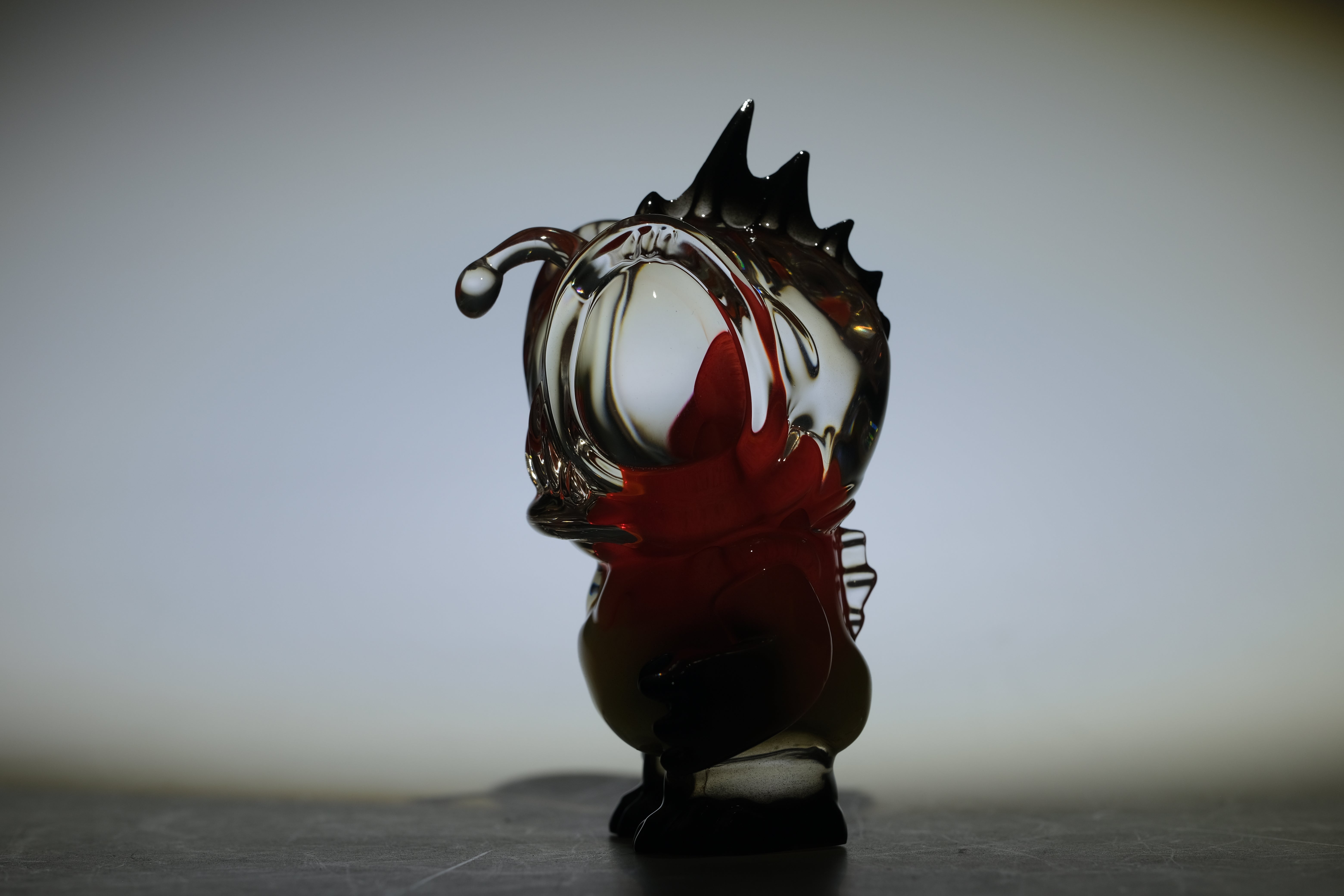 Angie Evo - Chicago Fire by 5th Turtle: A 3.5 abstract glass sculpture with smoky and red hues, featuring dynamic curves and spiky protrusions. Limited to 50 pieces.
