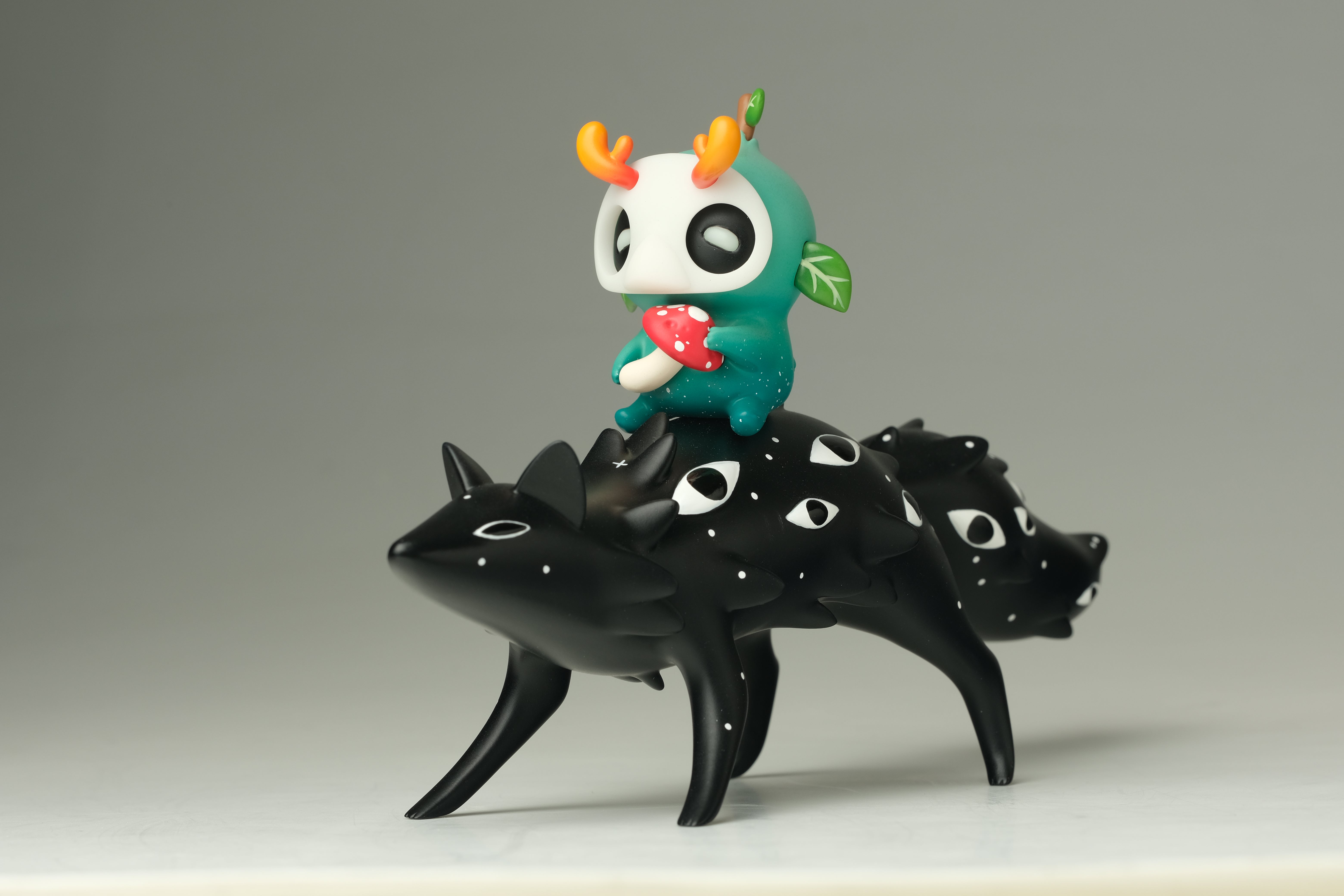Oracle & Muffin sculpture by Faunwood x Madkids features a black multi-faced quadruped with an antlered creature holding a spotted mushroom, crafted from high-grade resin.