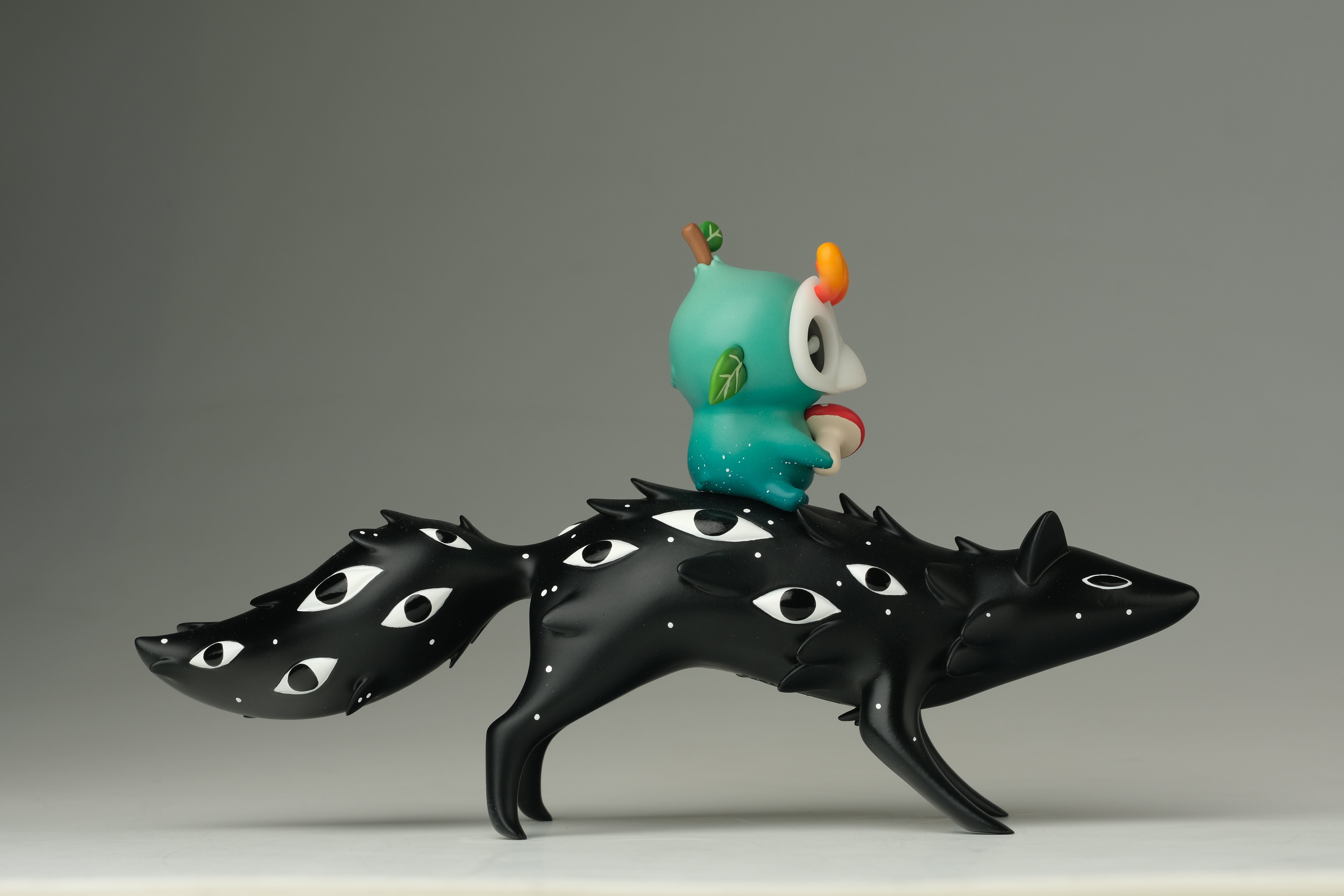 Oracle & Muffin by Faunwood x Madkids: A whimsical resin art toy featuring a black creature with eye-like markings and a tiny character holding a mushroom.