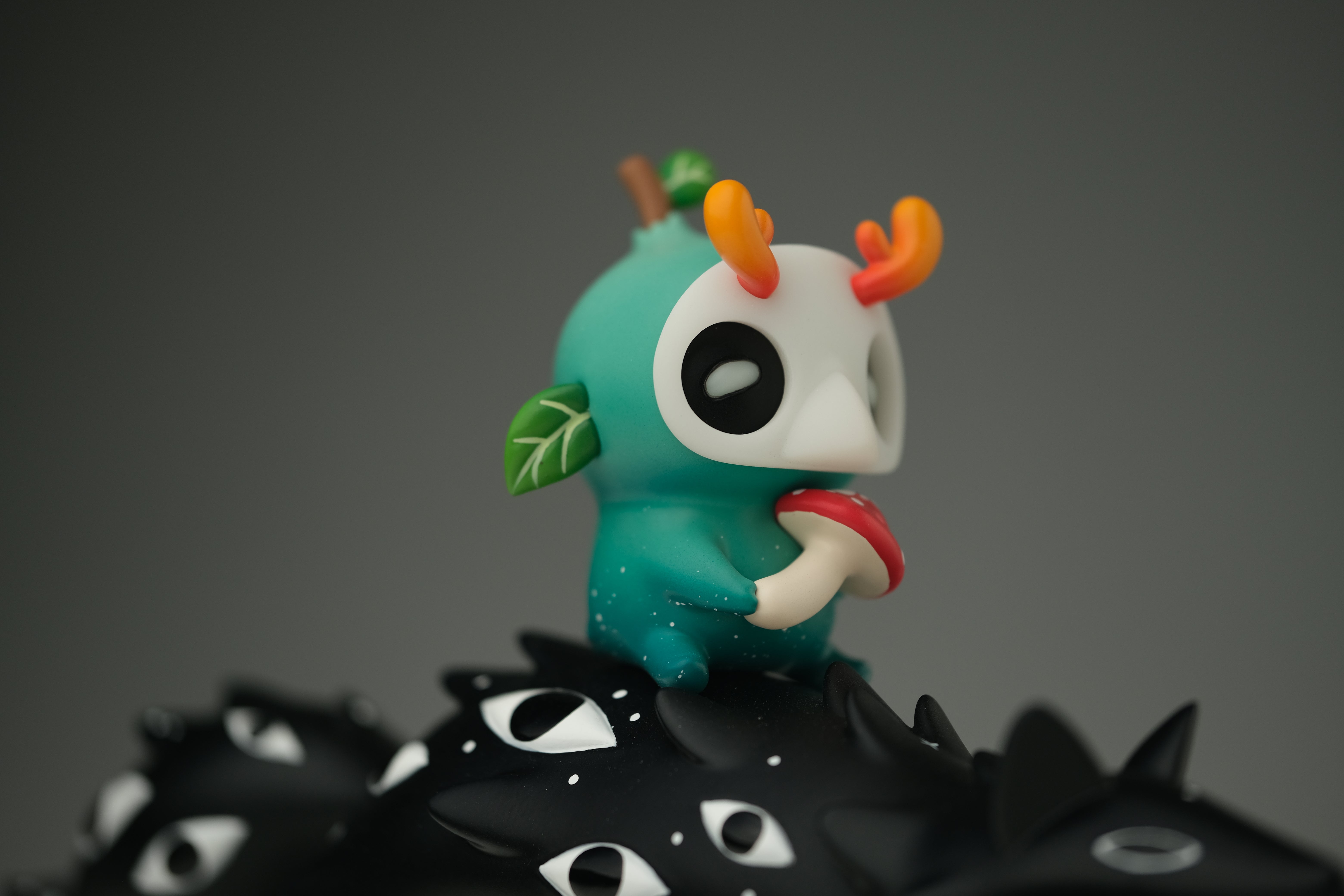 Oracle & Muffin by Faunwood x Madkids: A 7 teal art toy with a skull-like face, antler-horns, holding a mushroom, on a spiked base. Limited edition.