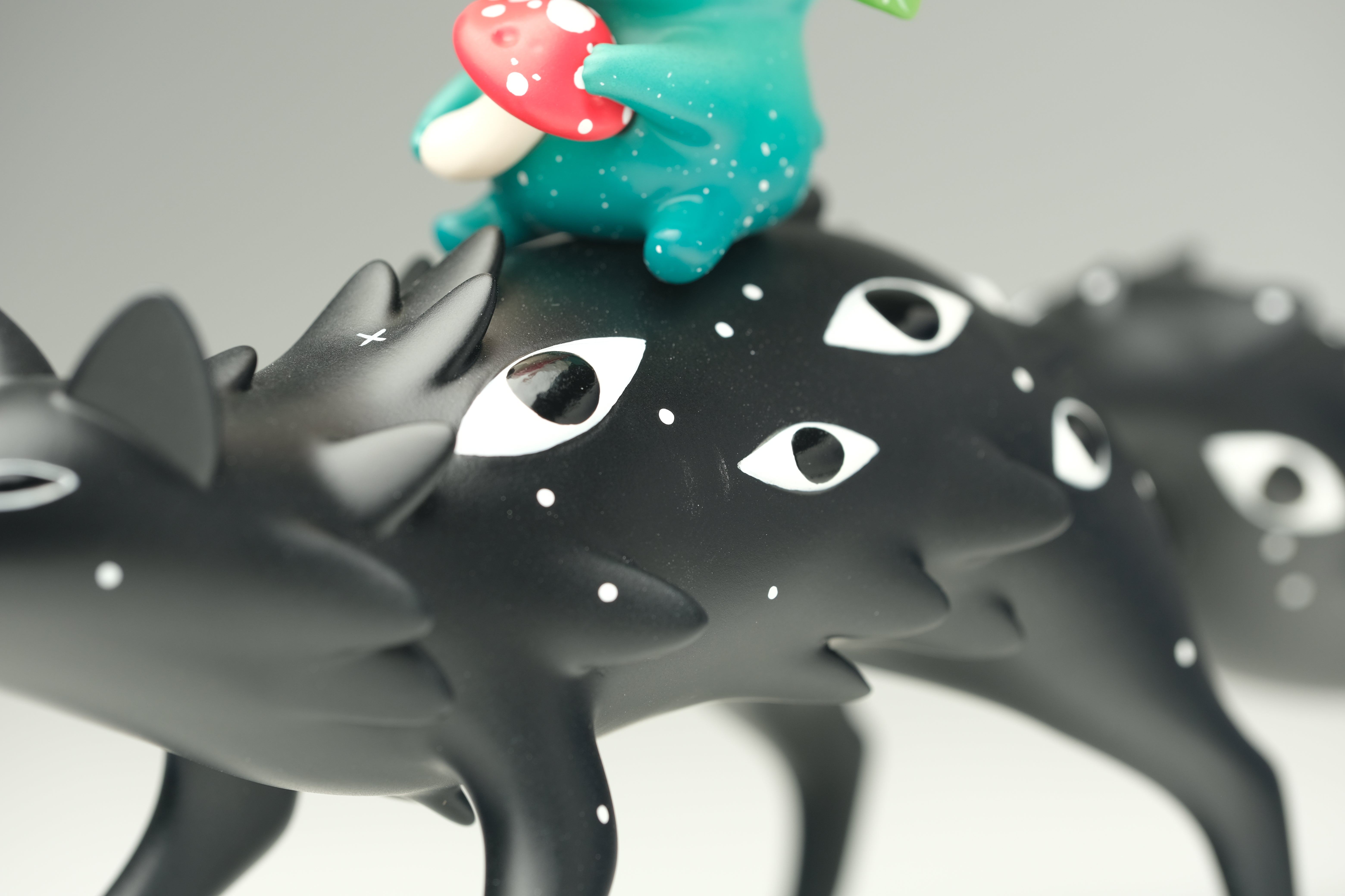 Oracle & Muffin by Faunwood x Madkids: matte-black creature with white eyes, spikes, multiple legs; aqua-green toad atop, holding red-and-white mushroom. Limited edition resin art toy.