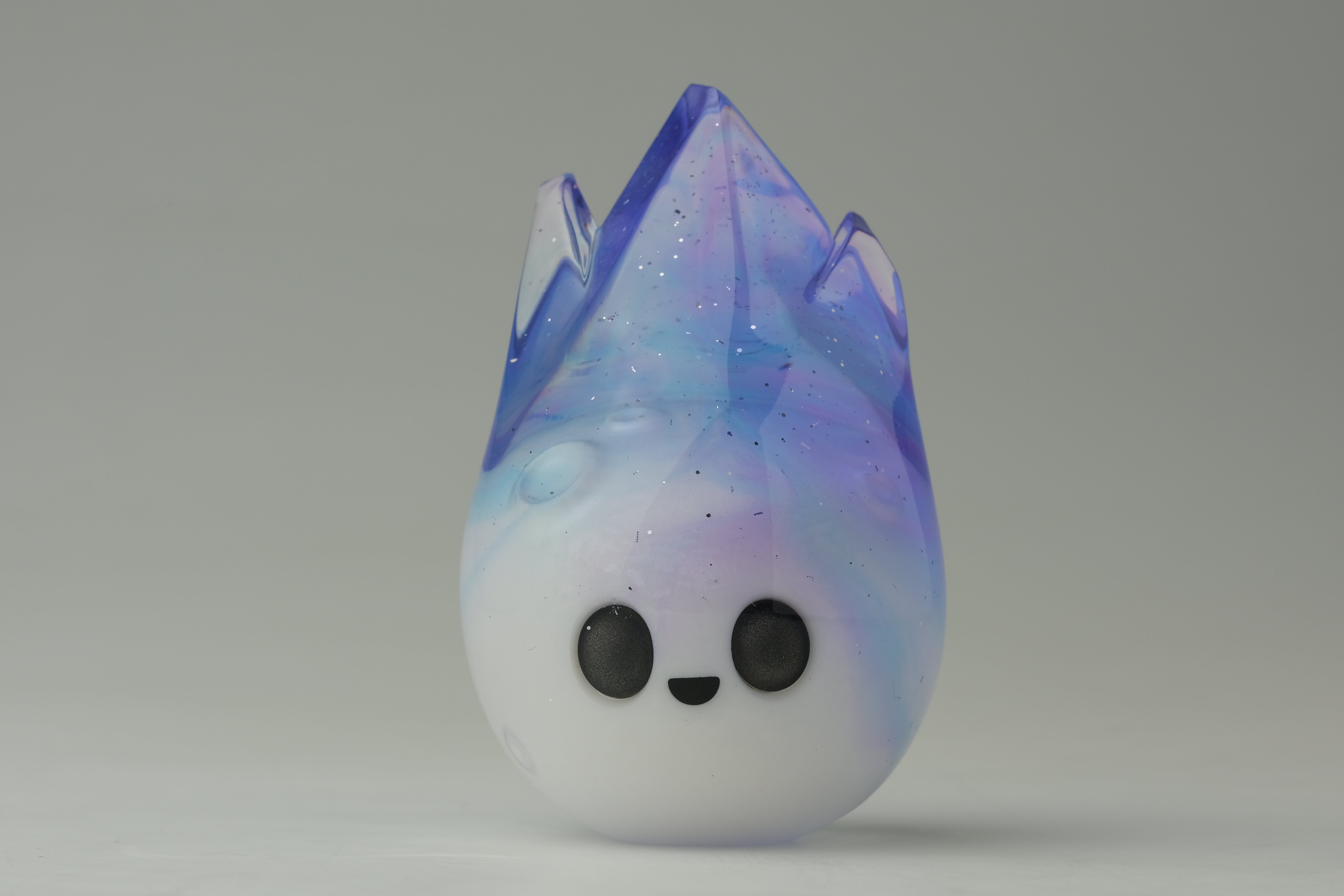 Aurora Cosmite by Yutoos: a 3.5 resin figurine with a cute face, featuring a white-to-purple-blue gradient, shaped like a stylized flame.