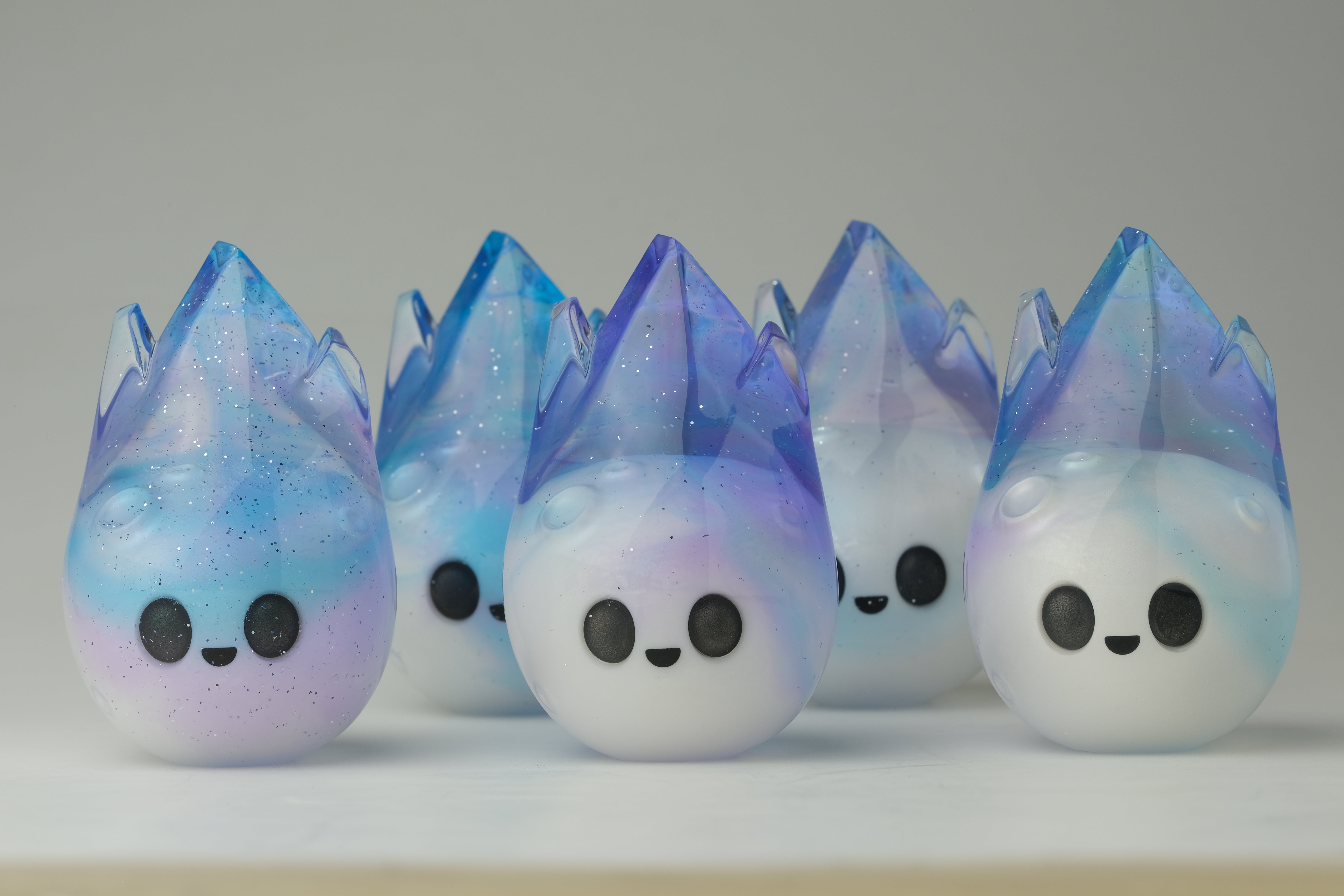 Aurora Cosmite by Yutoos: Five unique, hand-made resin figurines with whimsical teardrop designs, featuring sparkling crystal-like tops and cute cartoon faces, 3.5 each.