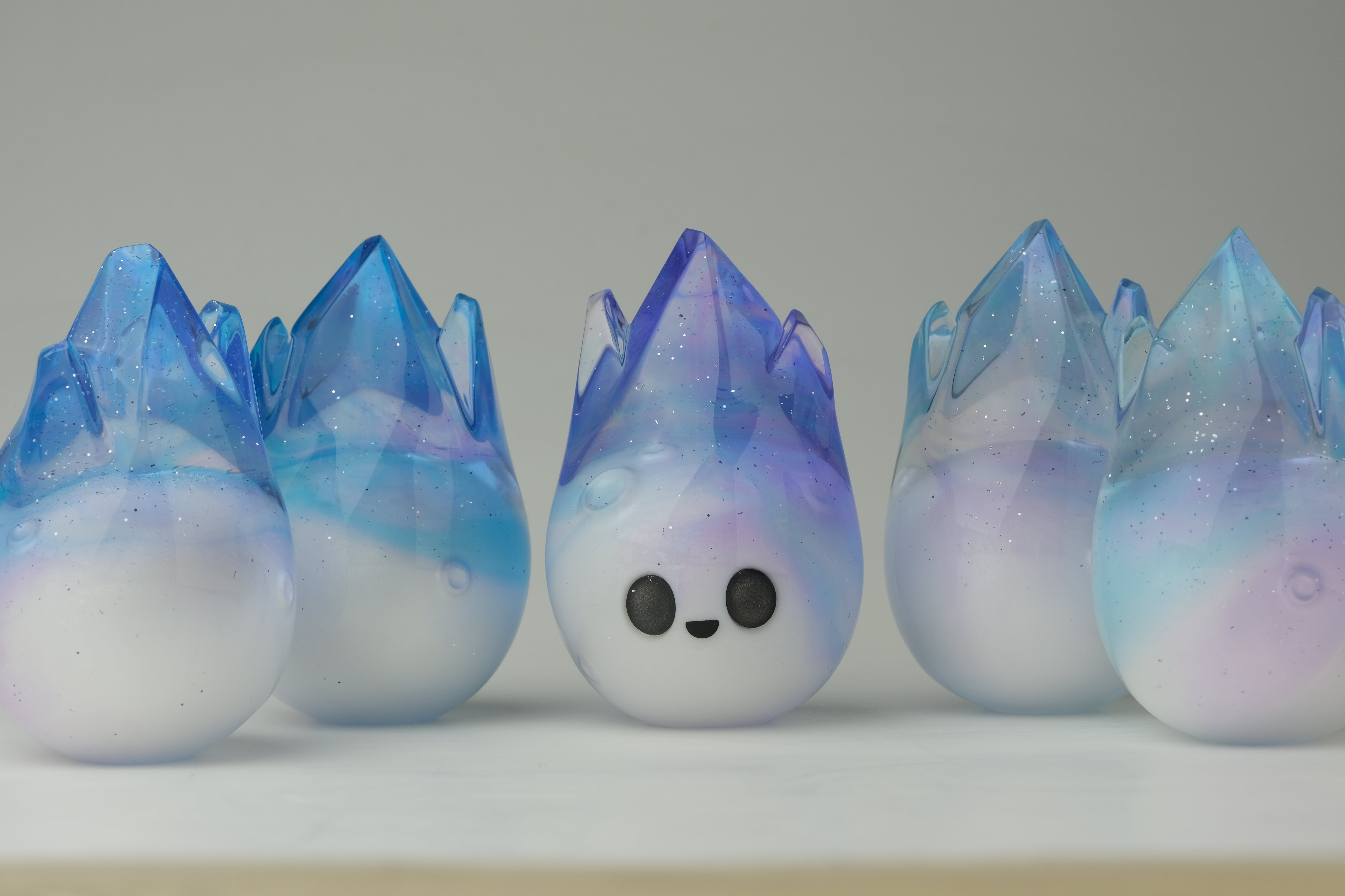 Aurora Cosmite by Yutoos: Six unique, hand-made resin droplet sculptures with crystalline tops. One features a smiling face, adding character to the collection.