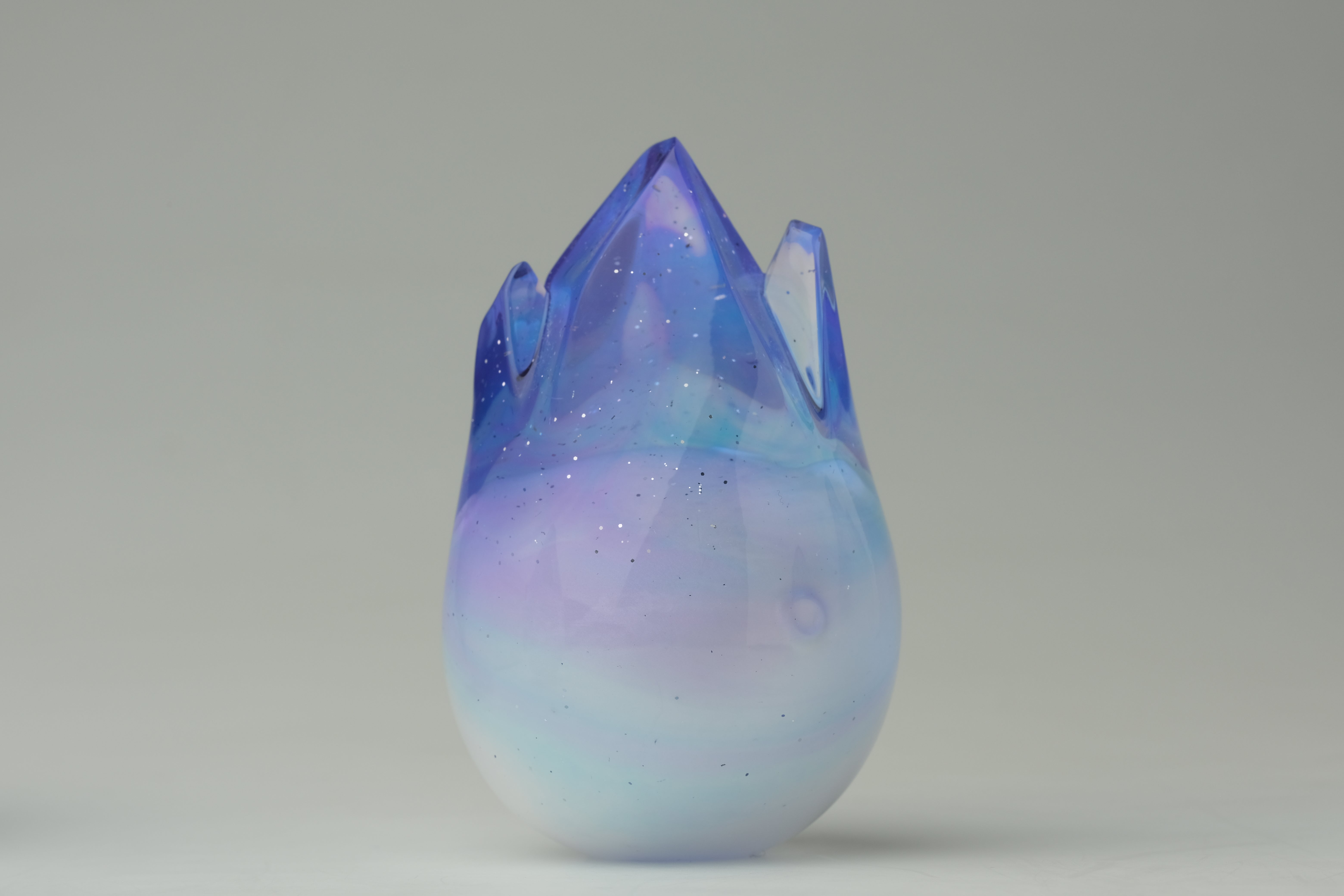 Aurora Cosmite by Yutoos: A 3.5 translucent resin teardrop sculpture with a jagged crown, featuring a unique galaxy-effect gradient. Limited edition of 50.