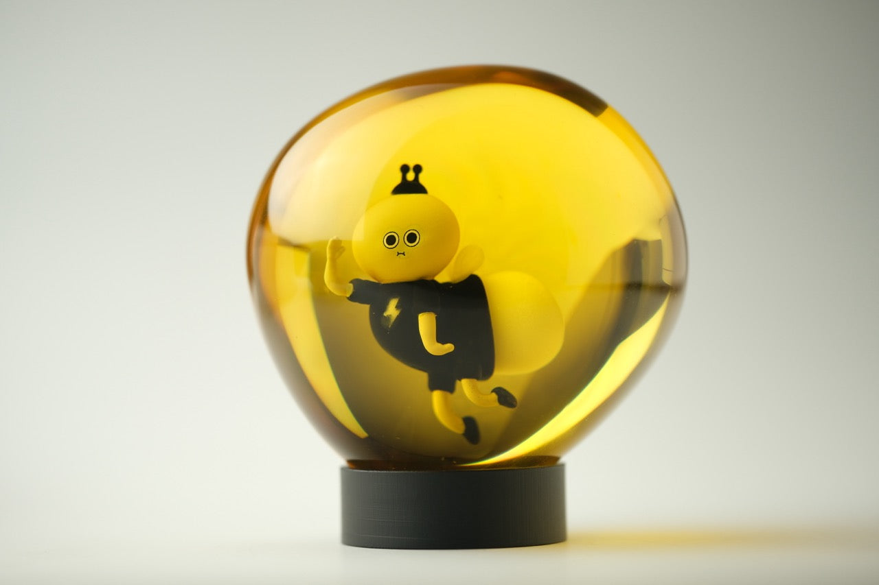 Lightning Bug by Sad Salesman: A whimsical, translucent amber resin globe with a stylized character inside, posed dynamically on a dark base, part of the Bugs in Amber series.