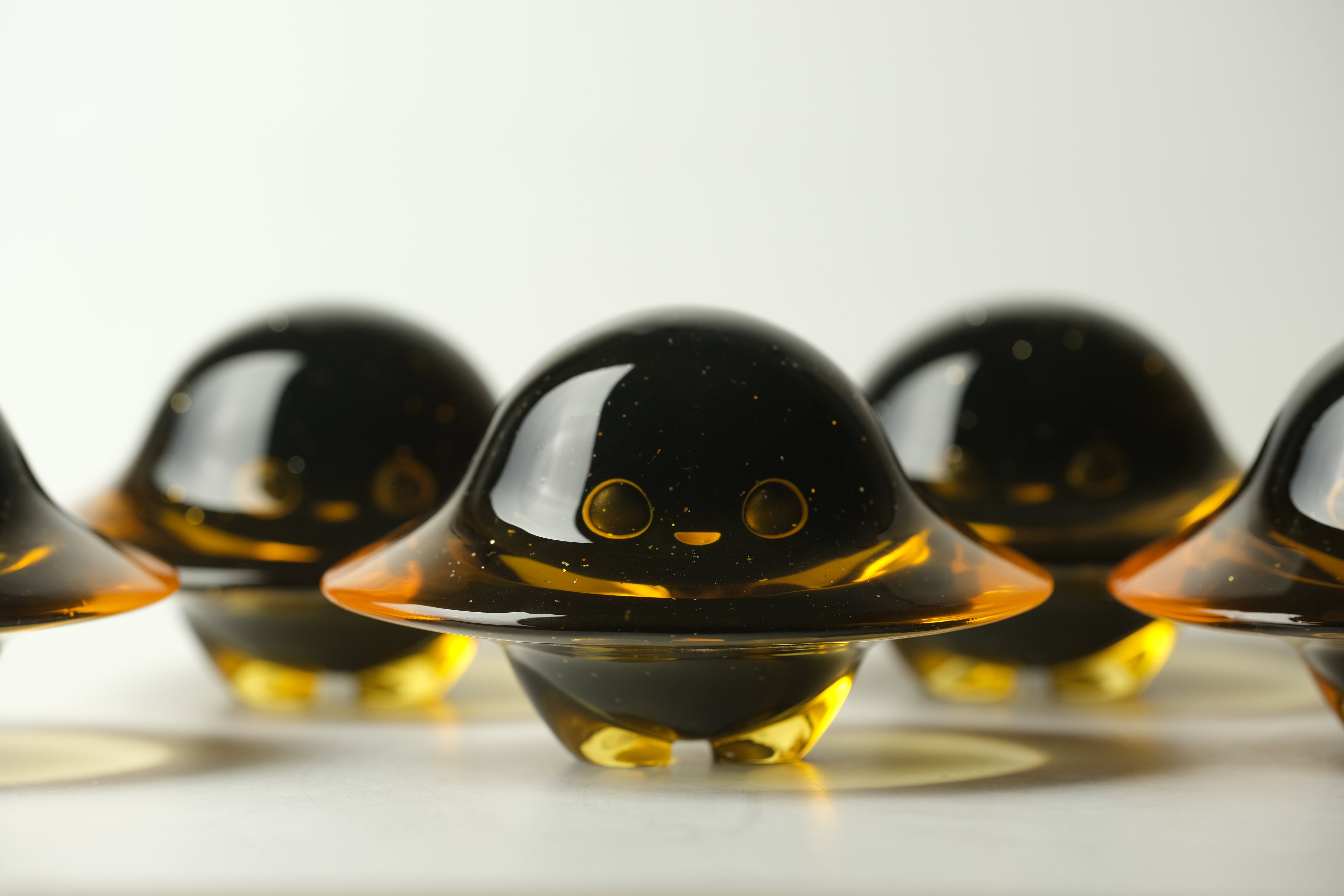 Darkmite by Yutoos: Small amber resin figurines with dome tops, smiling faces, and stubby legs. Limited edition art toy, each uniquely crafted, 3.5 inches tall.