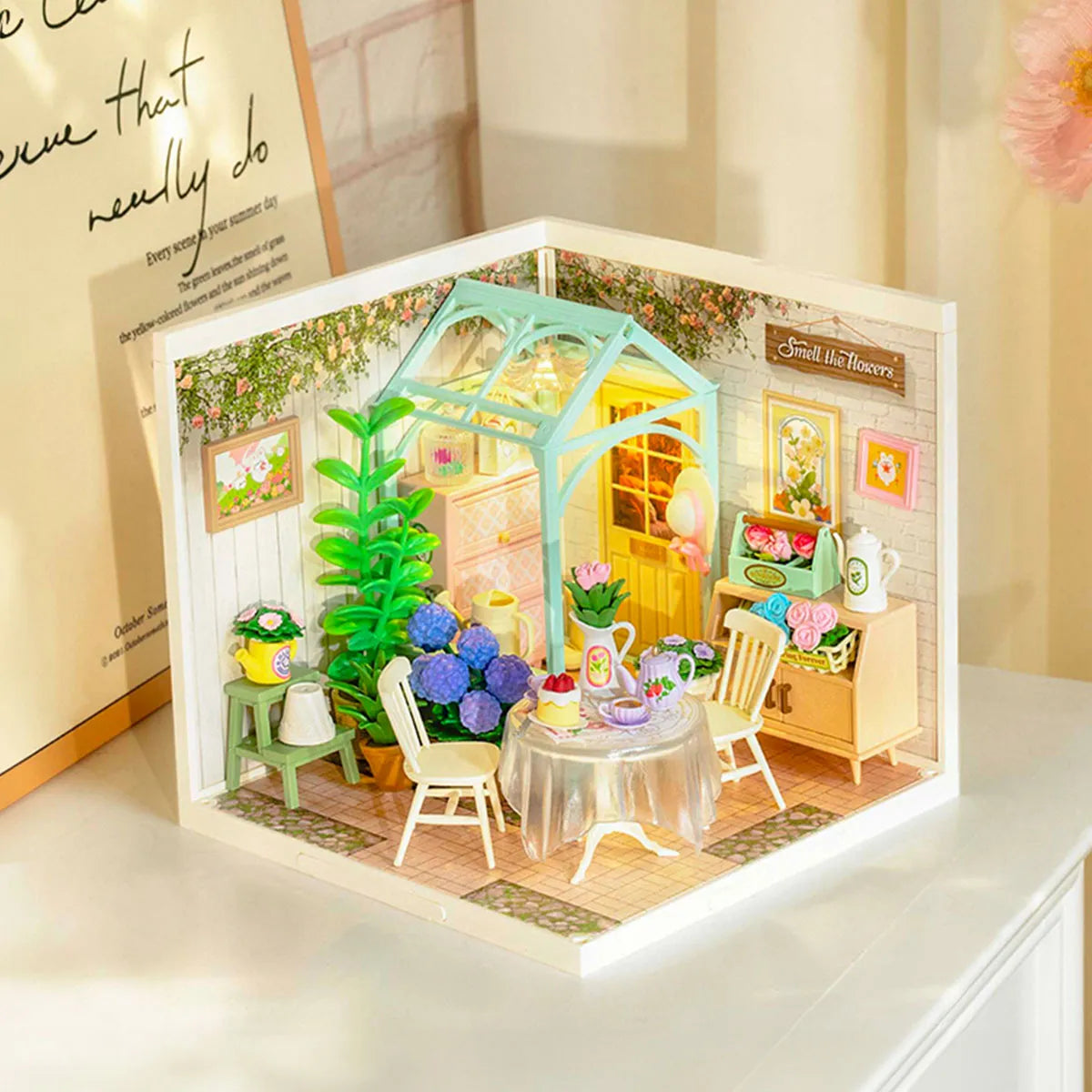 DW013B Blooming Tea Garden Miniature House featuring a detailed tea table, chairs, plants, and toy greenhouse, ideal for a relaxing DIY garden scene.