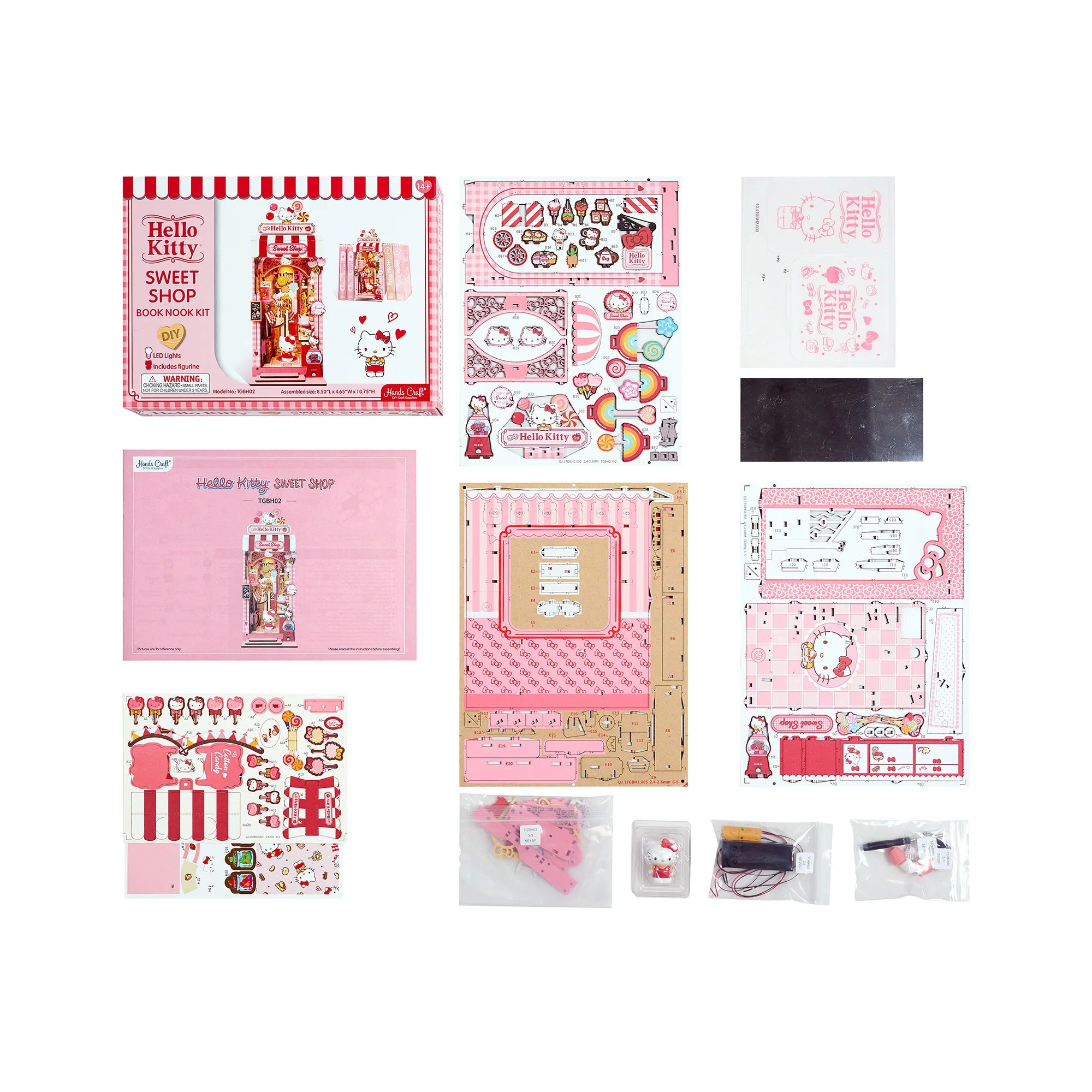 Hello Kitty® Sweet Shop Booknook kit components, including instruction sheet, chipboard panels, decorative stickers, tiny figurine, and LED parts for assembly.