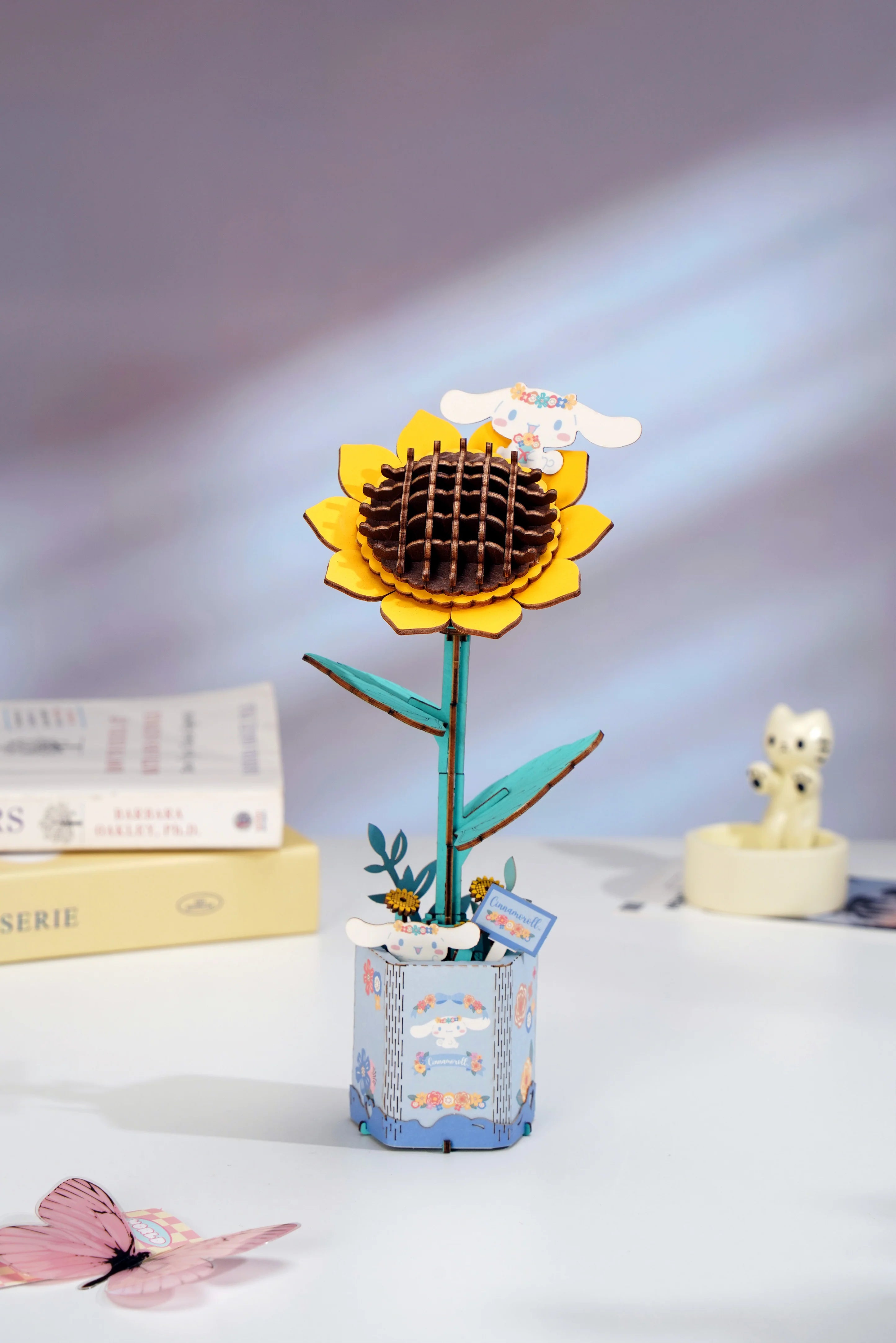 Hello Kitty® and Friends Cinnamoroll Sunflower 3D Wooden Puzzle Kit featuring a sunflower design with Cinnamoroll, in a pastel-blue pot, and a pink butterfly ornament.
