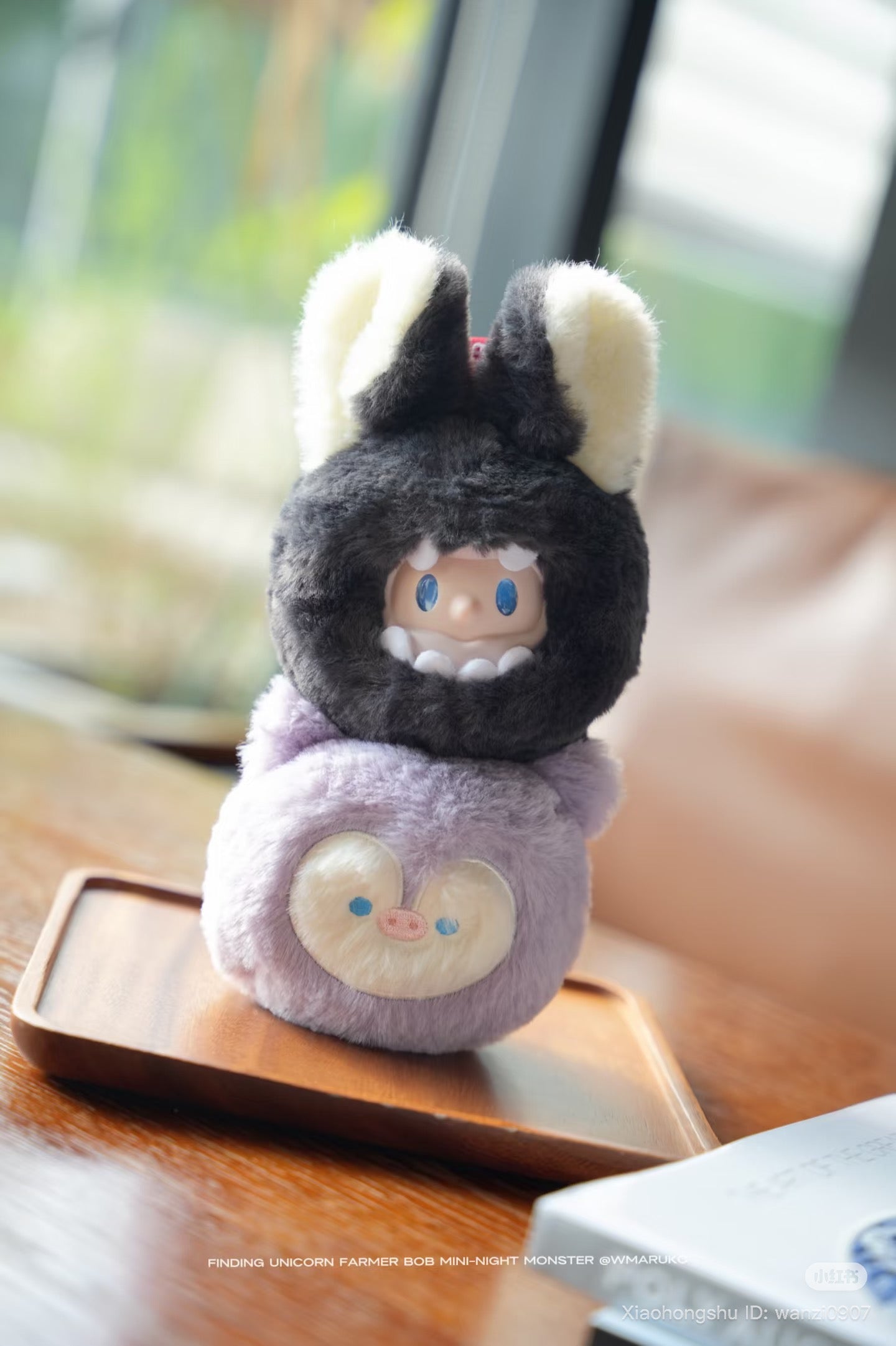 Farmer BOB MINI-NIGHT Monster Blind Box Plush Keychain featuring a lavender cube creature and a fuzzy monster hood on a wooden tray.