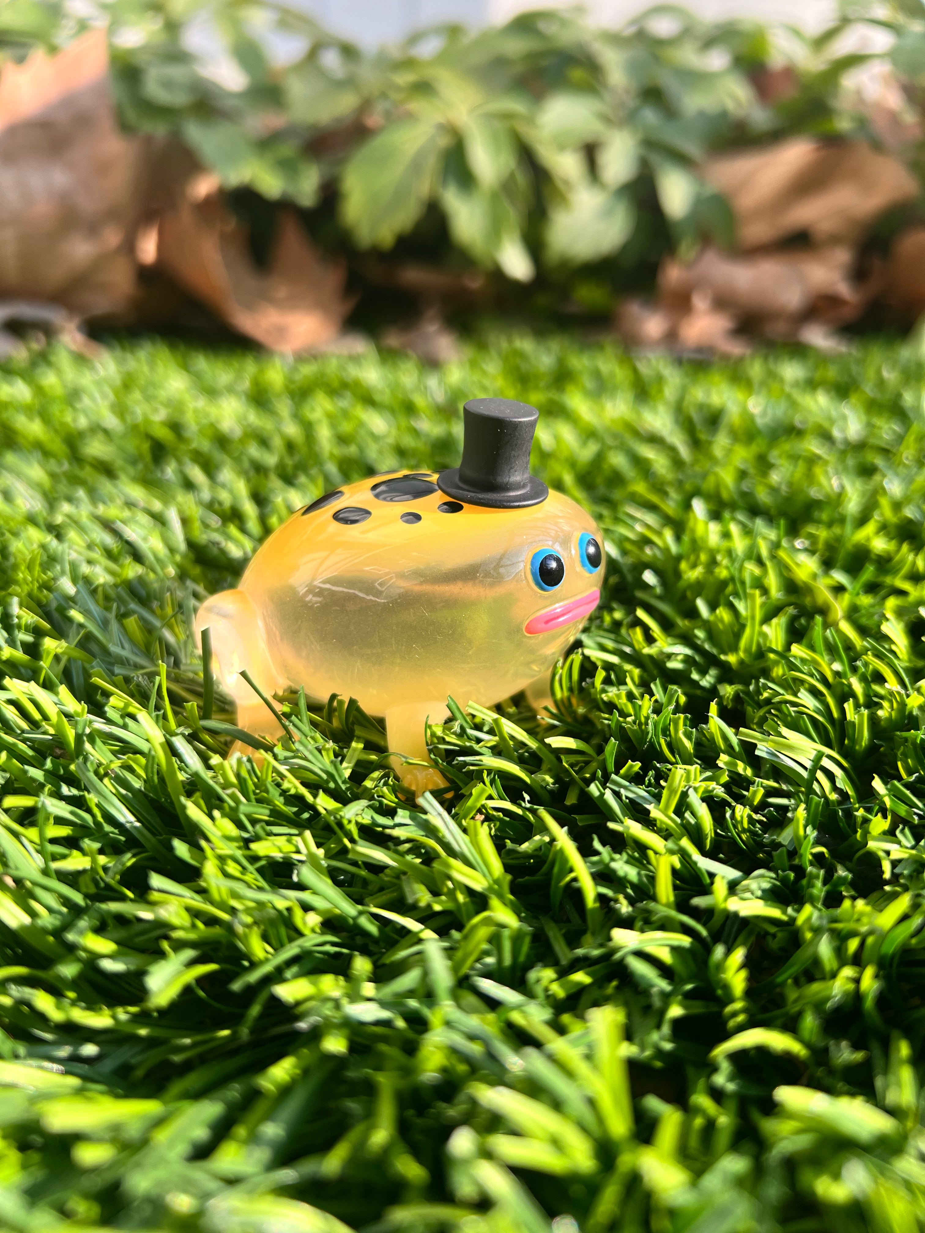 Poison Dart Frod by Sad Salesman: A small resin frog toy with a top hat, set on grass. Limited edition of 100 pieces, includes five PVC hats.