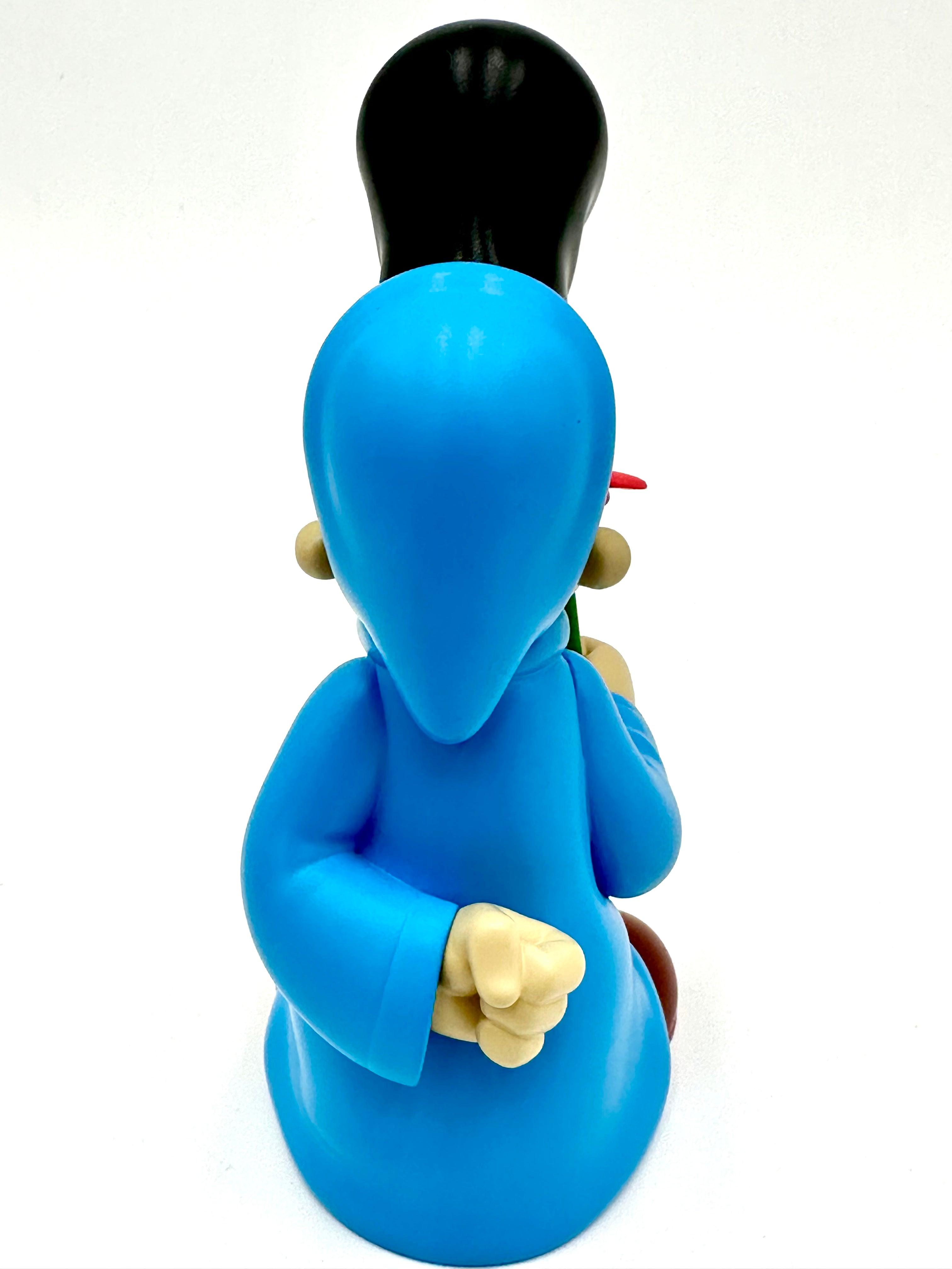 Stylized vinyl figure Before I Go by Ezra Brown, 6-inch resin, in a blue robe, holding a red prop, viewed from behind.
