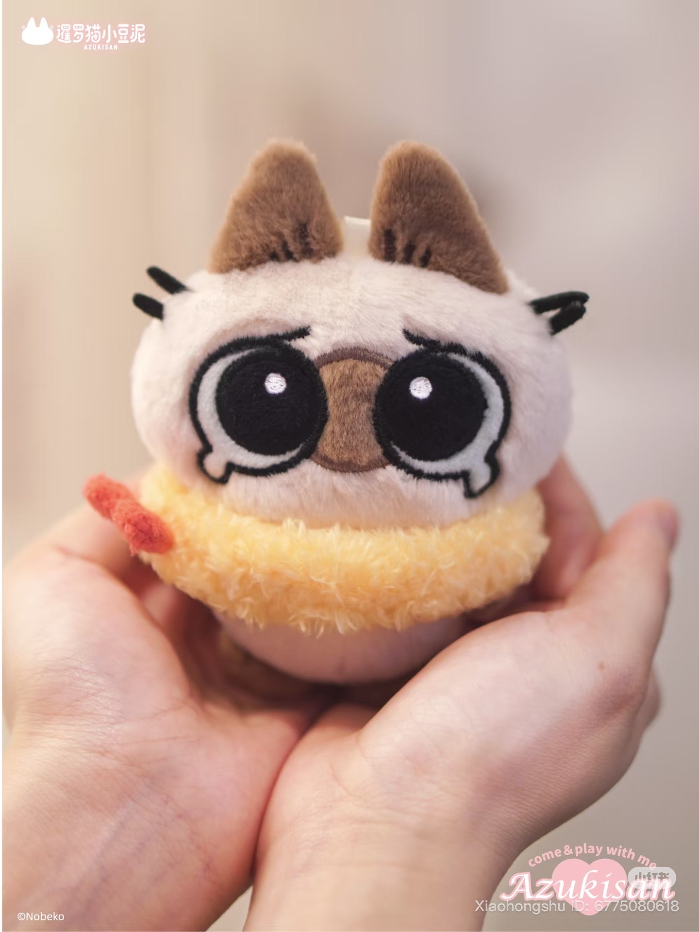 Azukisan's Daily Life Series plush pendant, a round cat with big eyes and a yellow swim ring, gently cupped in hands.