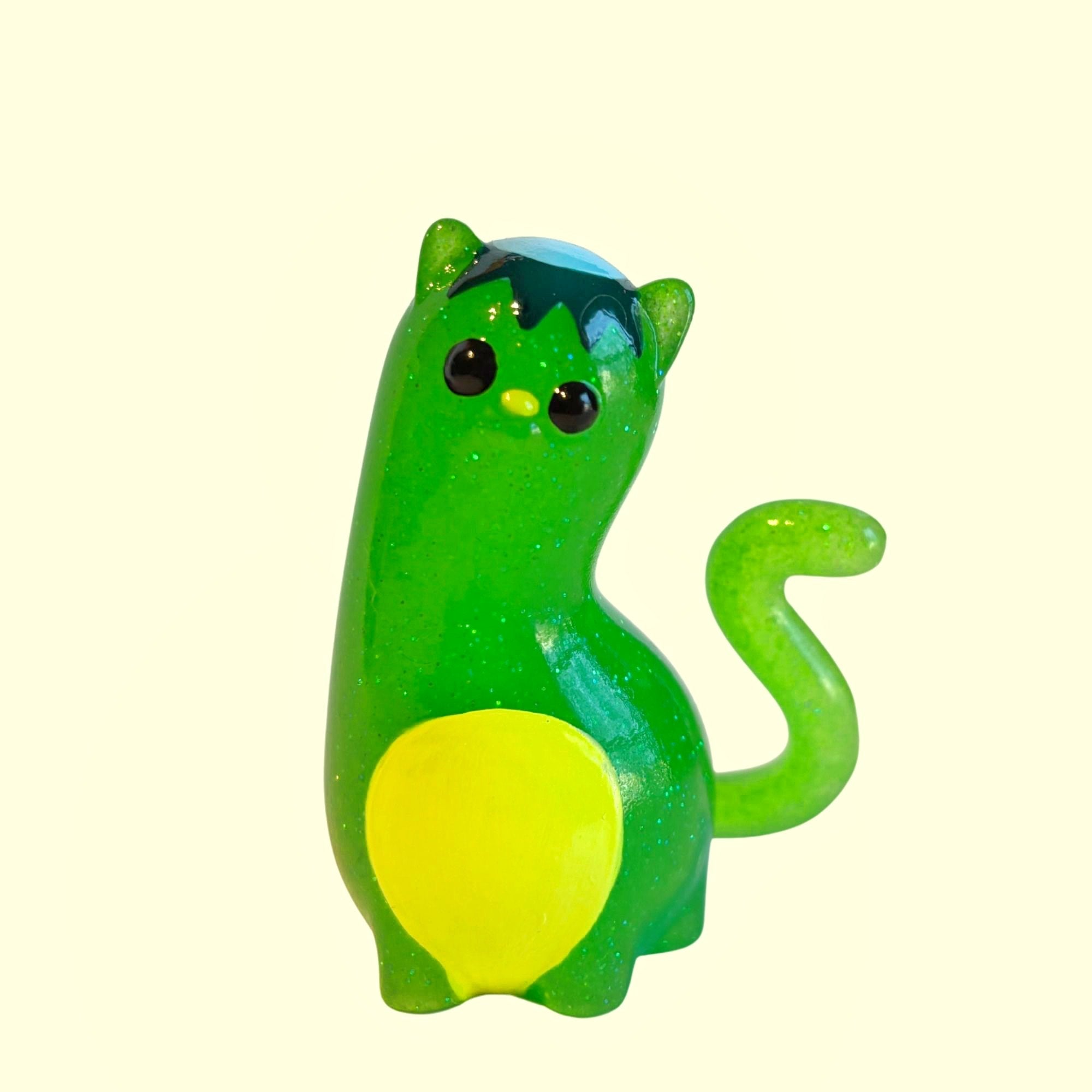 Spencer by Ghost Fox Toys: A small, hand-painted fantasy creature figurine with horns, button eyes, and a curly tail, featuring a sparkly green, toy-like appearance.