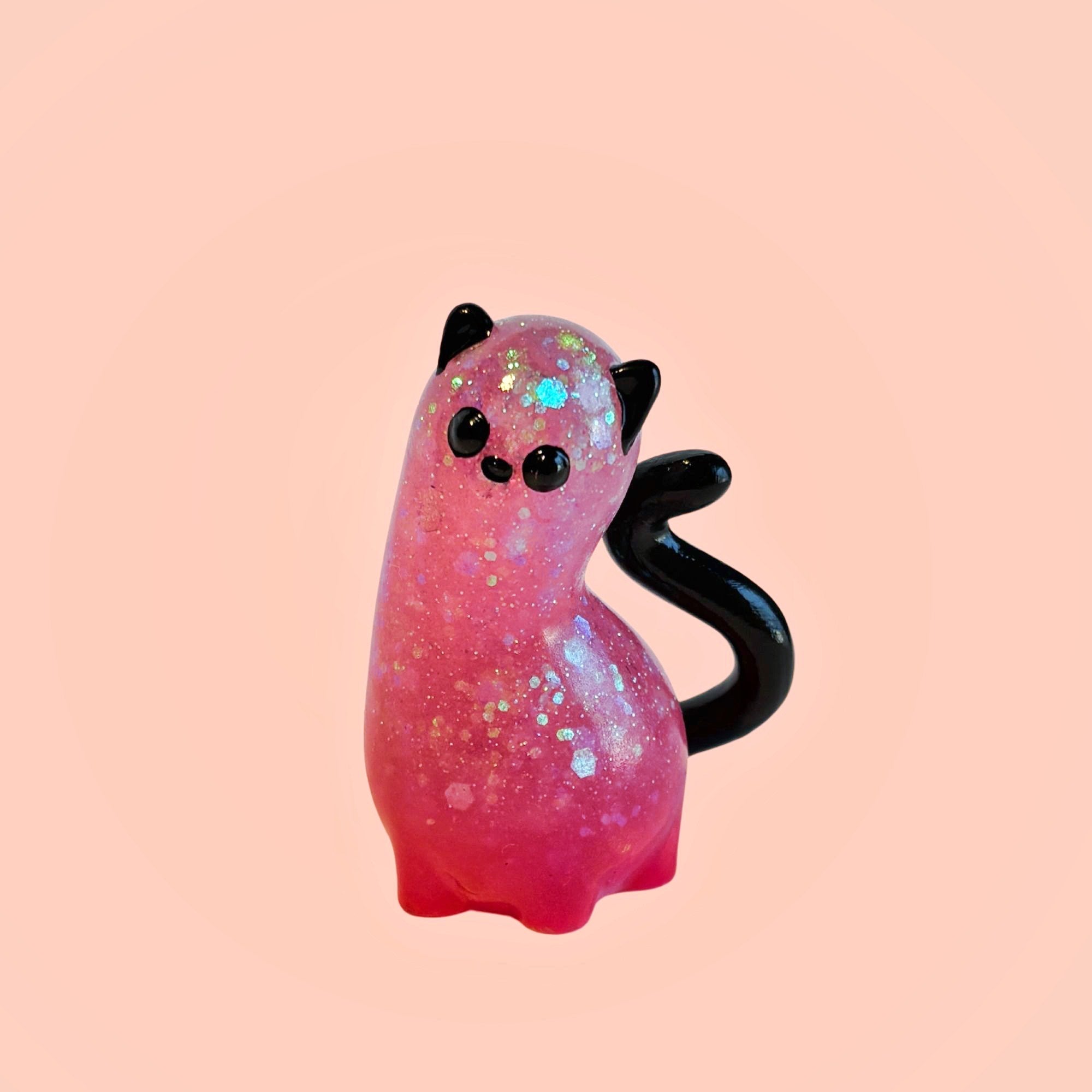 Spencer by Ghost Fox Toys: a small, stylized resin cat figurine with iridescent glitter, simple black features, and a glossy swirled tail.