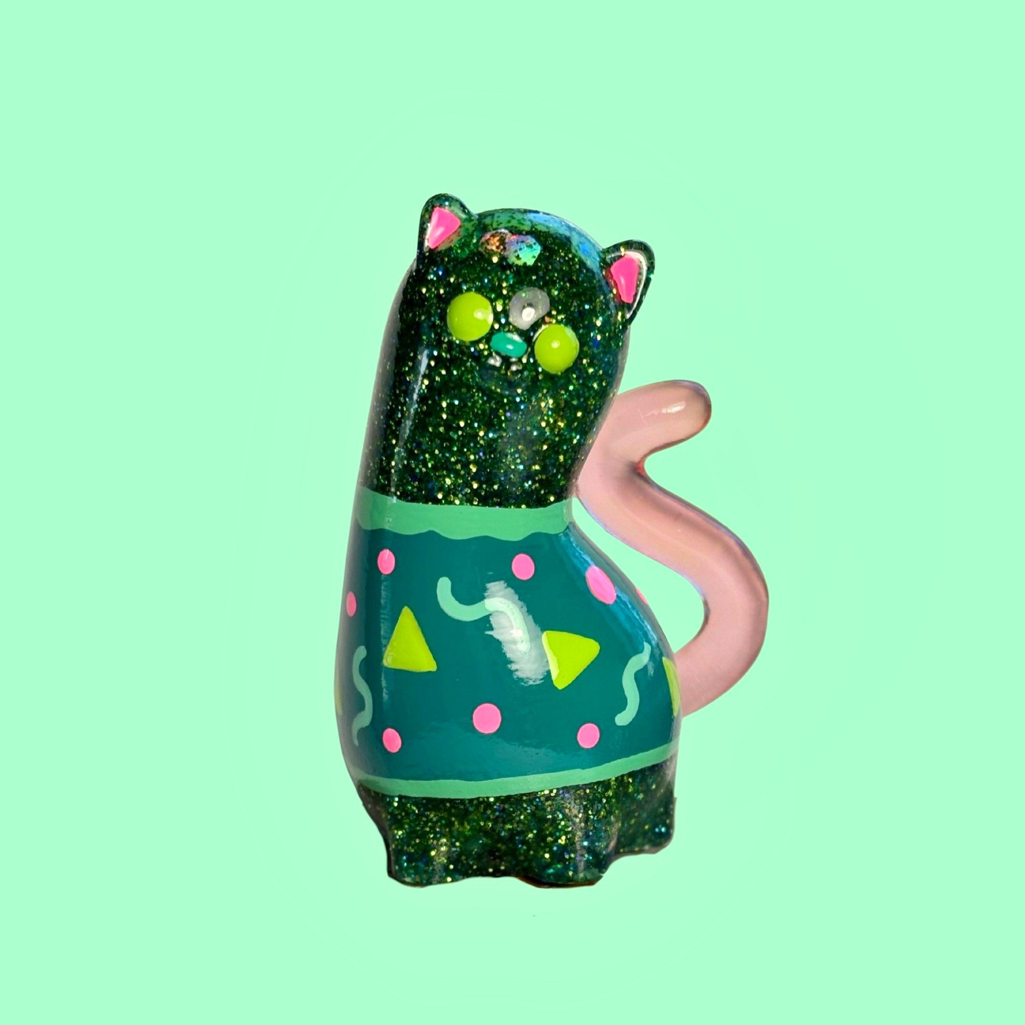 Spencer by Ghost Fox Toys: A cat-shaped figurine with a glittery body, teal midsection adorned with neon-pink dots, yellow triangles, and mint squiggles.