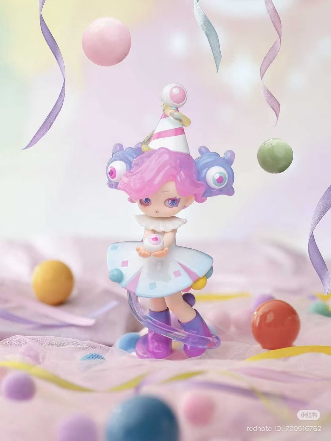 Memimo-Unusual Dream Blind Box Series Figure with bubblegum-pink hair, party hat, candy skirt, and eyeball motifs, holding a pastel orb, amidst floating spheres.