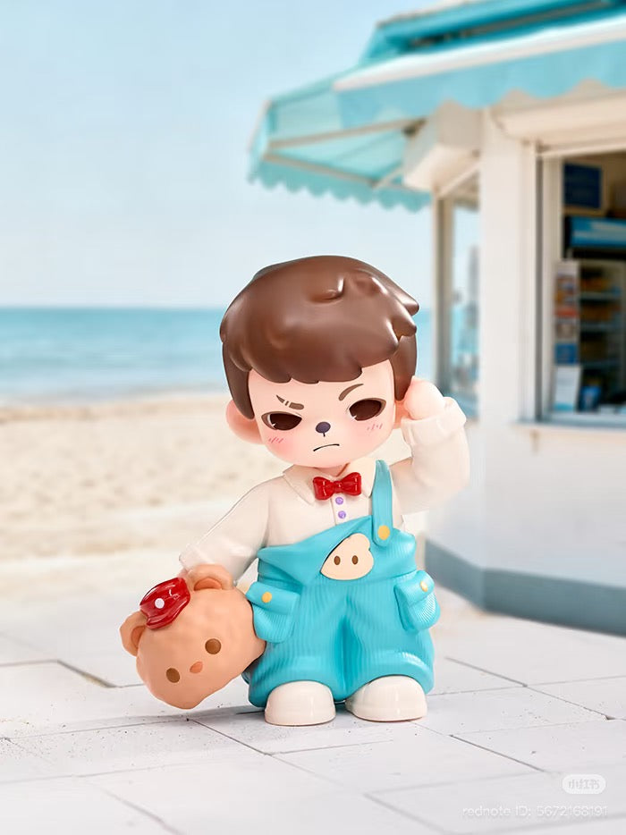 Rayan Let't Date Series figure: a grumpy boy in teal overalls with teddy bear, set against a beach backdrop. Preorder from Strangecat Toys.