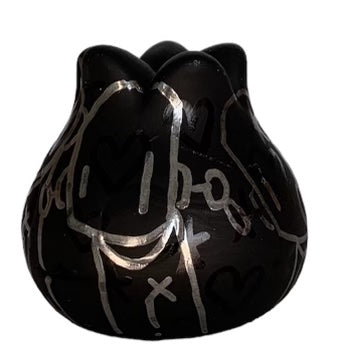 A black vase with silver writing, a black object, and a graffiti design on vinyl art by Chris RWK.