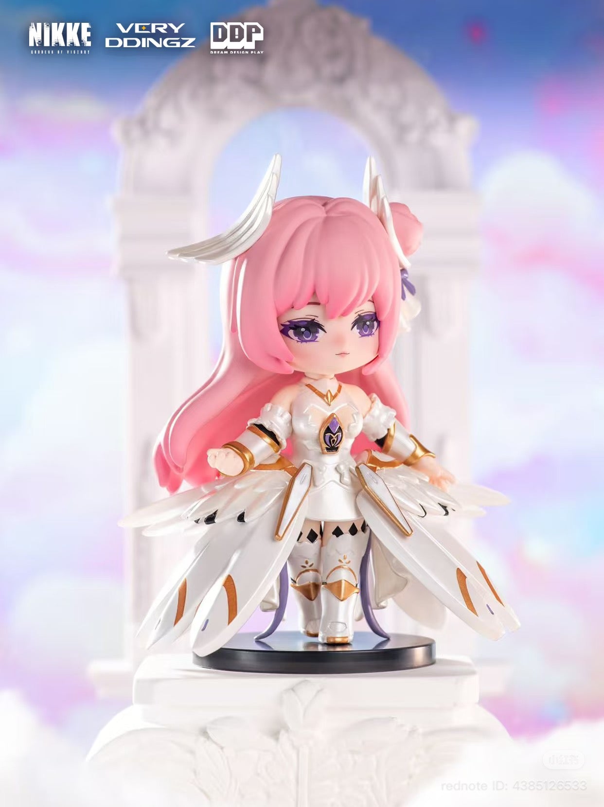 Chibi figurine of NIKKE: Goddess of Victory in white-and-gold outfit, part of a blind box series, posed on a black base under a decorative arch.