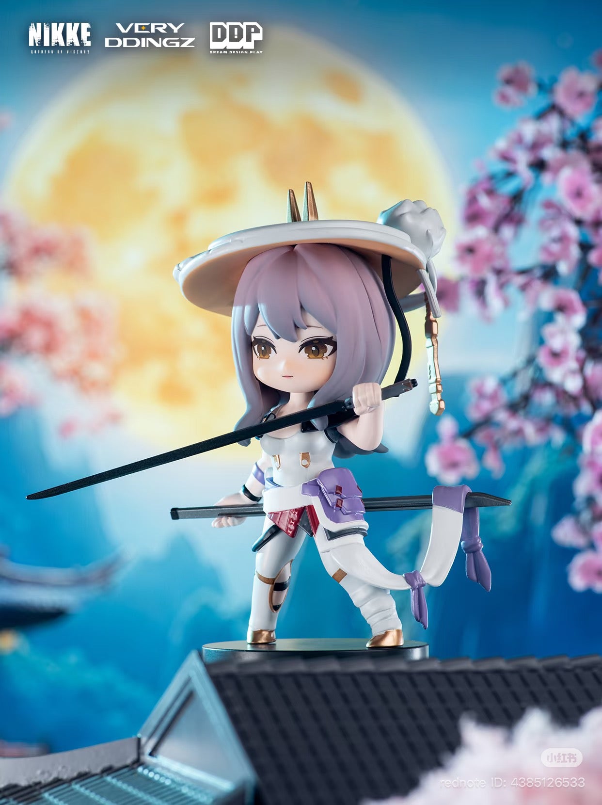 Chibi-style figure from NIKKE: Goddess of Victory Blind Box, featuring a samurai-themed character with swords, straw hat, and cherry blossom backdrop. Preorder for Q4 2025.