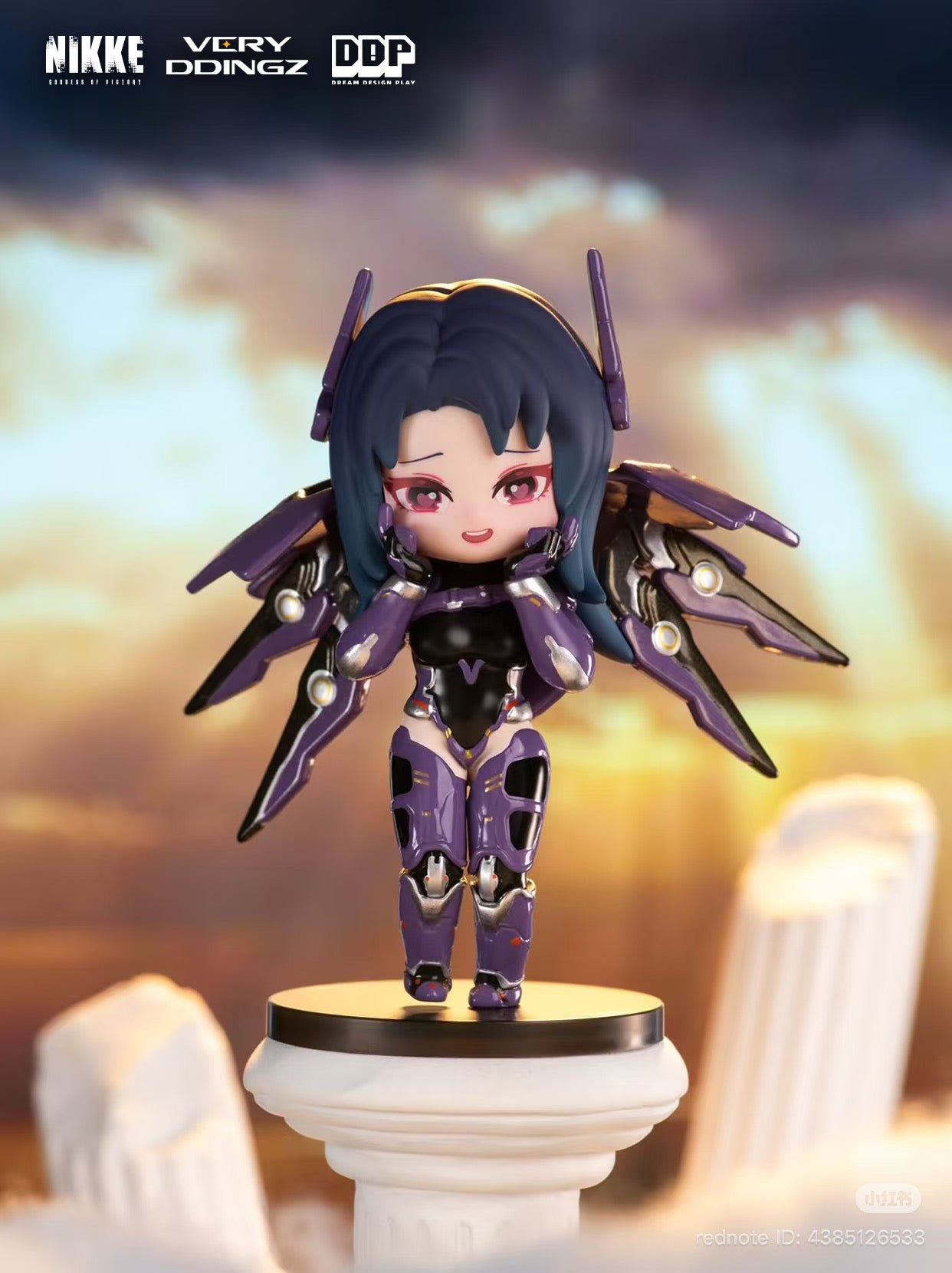 Chibi-style figurine of NIKKE: Goddess of Victory in black-purple armor, posed playfully on a Greco-Roman column pedestal; promotional for Strangecat Toys' blind box series.