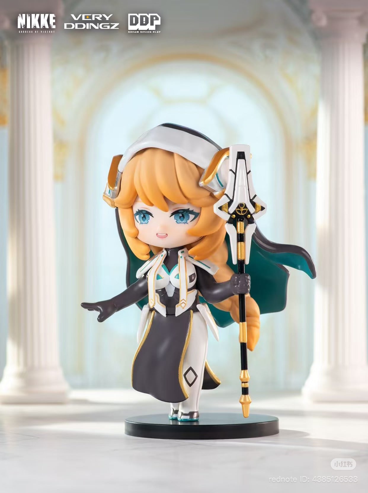 NIKKE: Goddess of Victory Blind Box figurine, featuring a chibi character with golden-blonde hair, holding a futuristic staff, in sleek black, white, and gold attire.