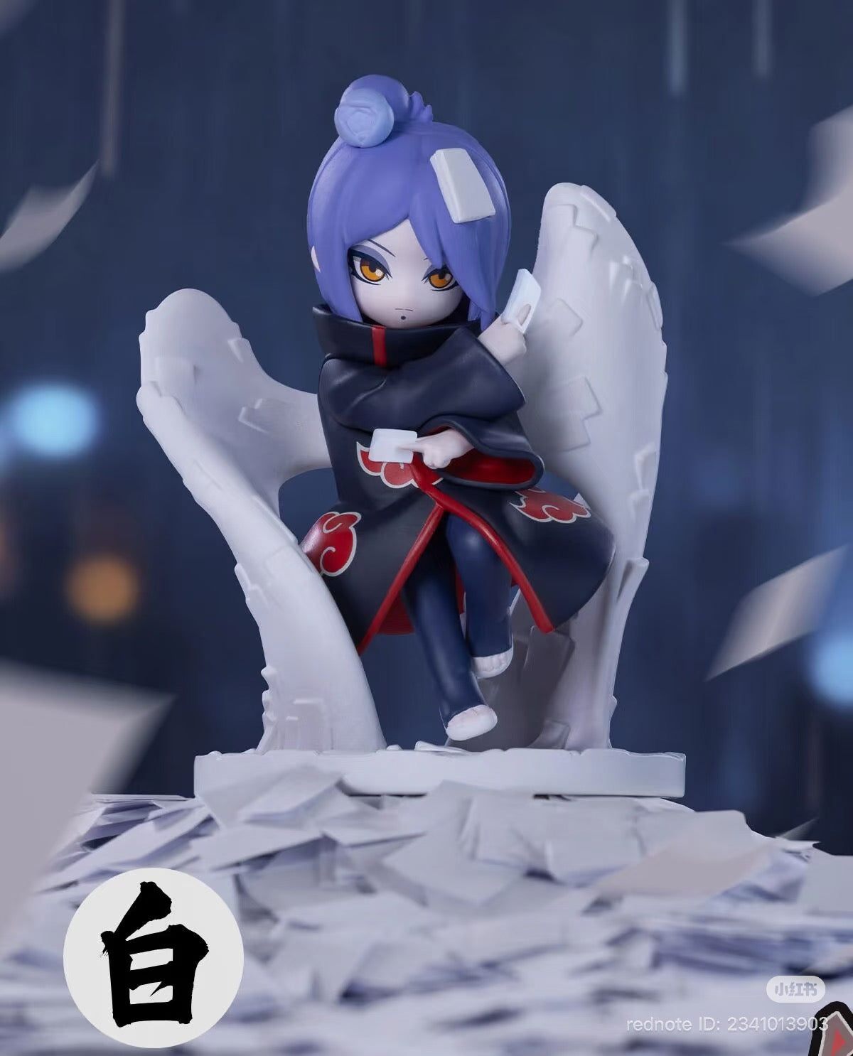 Chibi-style Konan figure from Naruto: Shippuden Series, featuring Akatsuki cloak, paper wings, and seals, surrounded by swirling sheets. Preorder collectable statue.