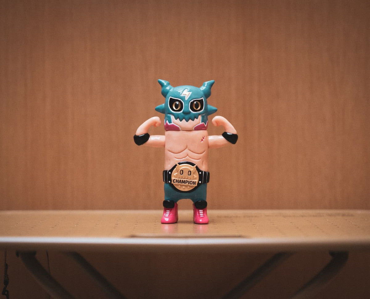 OWEN The Champion by ODOM - Preorder: 12cm vinyl luchador figurine flexing muscles, wearing teal mask, championship belt. Estimated shipping by Jan 2026.