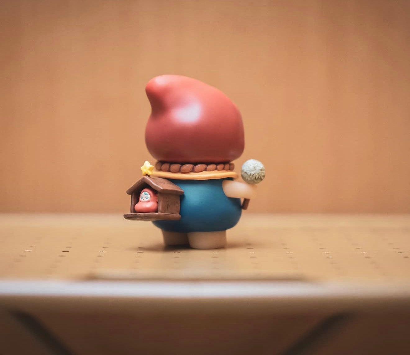 Pucky Poko figurine with red hat, blue tunic, holding a grey staff, and a mini wooden stable on its back. Preorder, ships by Jan 2026.