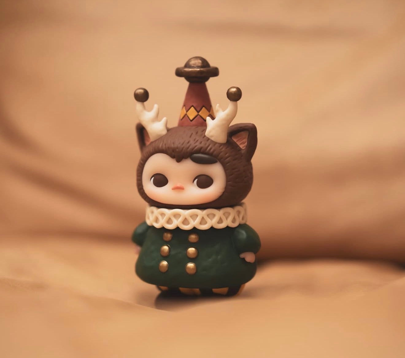 Pucky x Kaori Morris Pucky figurine, featuring a chibi character with antlered hood, fox ears, and conical hat, in a green coat. Preorder for Jan 2026.
