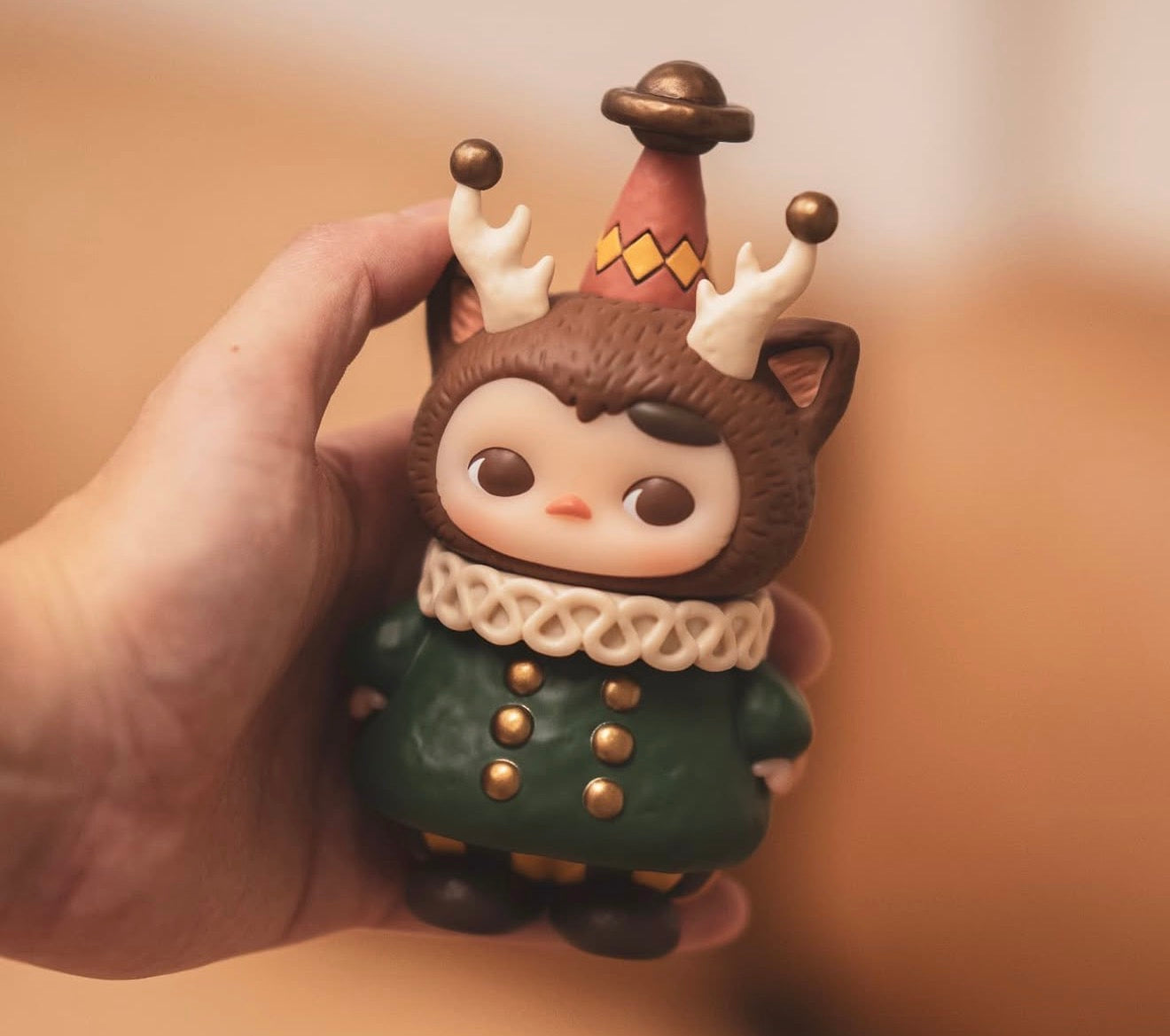 Pucky x Kaori Morris Pucky collectible figure, featuring a compact character with antlers, party hat, and green coat, held in hand for preorder.