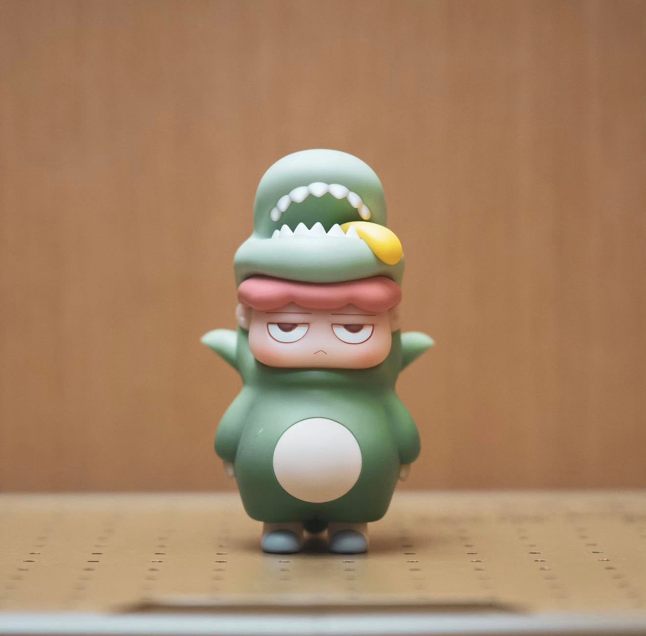 Poh Dino Moss by Vin figurine in green dinosaur costume, featuring pink-haired character with half-lidded eyes. Preorder, 16.5cm vinyl.