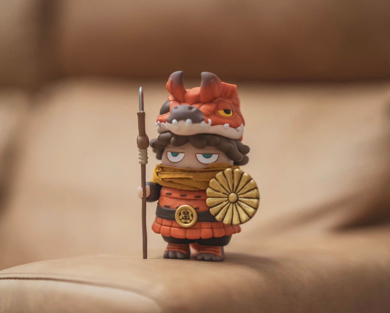 Poh x Booker Warrior collectible: chibi samurai with dragon helmet, red armor, spear, and gold shield, posed on a tan couch. Preorder now; ships January 2026.