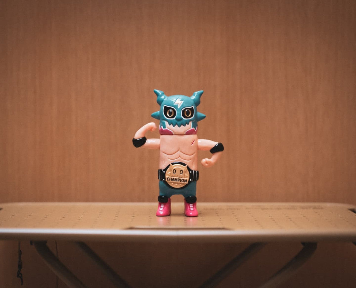 OWEN The Champion by ODOM vinyl action figure, 12cm, preorder. Features a horned mask, muscular build, Champion belt, flexed arms, and colorful wrestling attire.