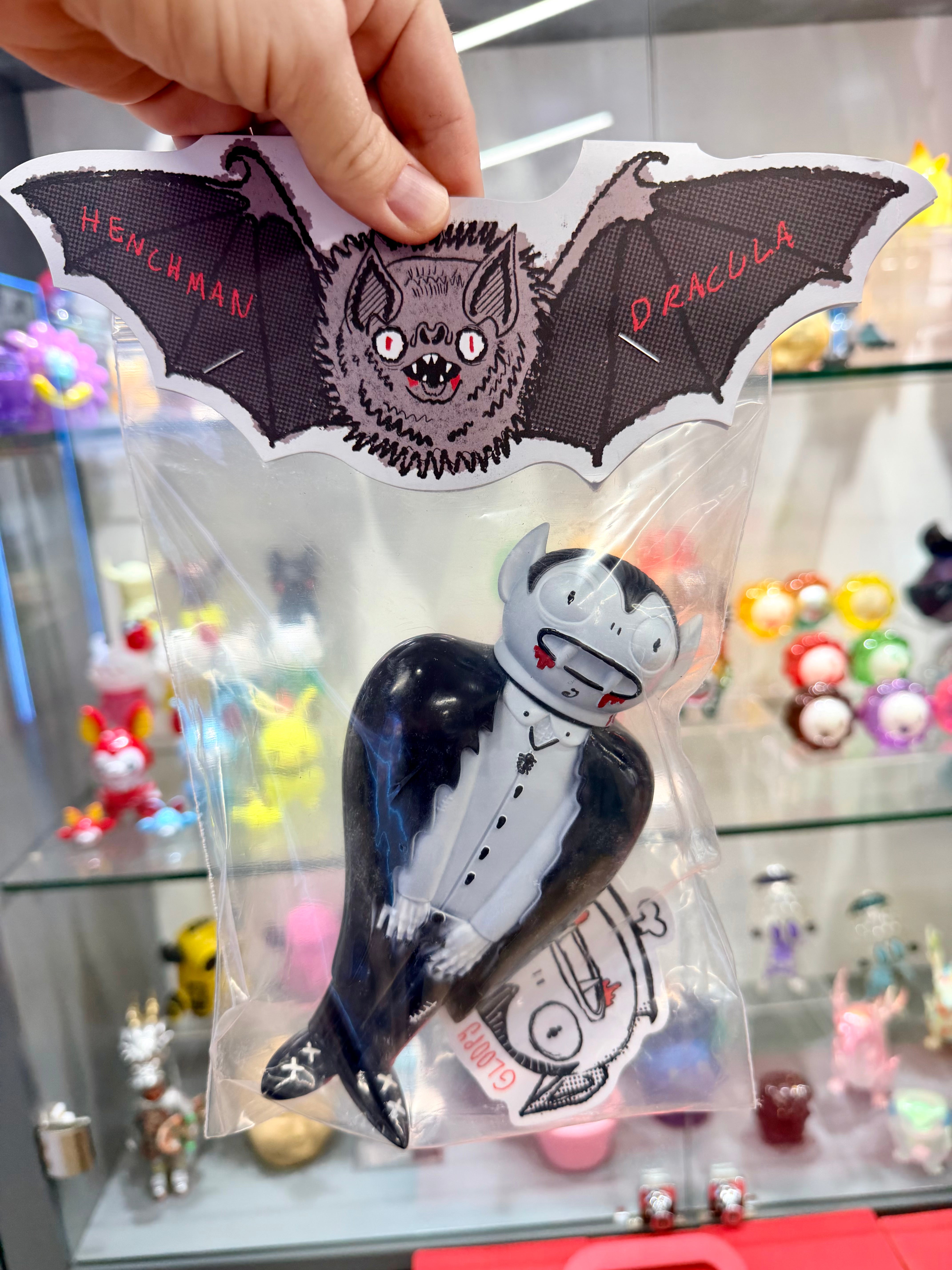Henchman Dracula vinyl toy in clear packaging with bat-wing header, showcasing a detailed, cartoonish design by Gloopy Goblin, ideal for collectors.