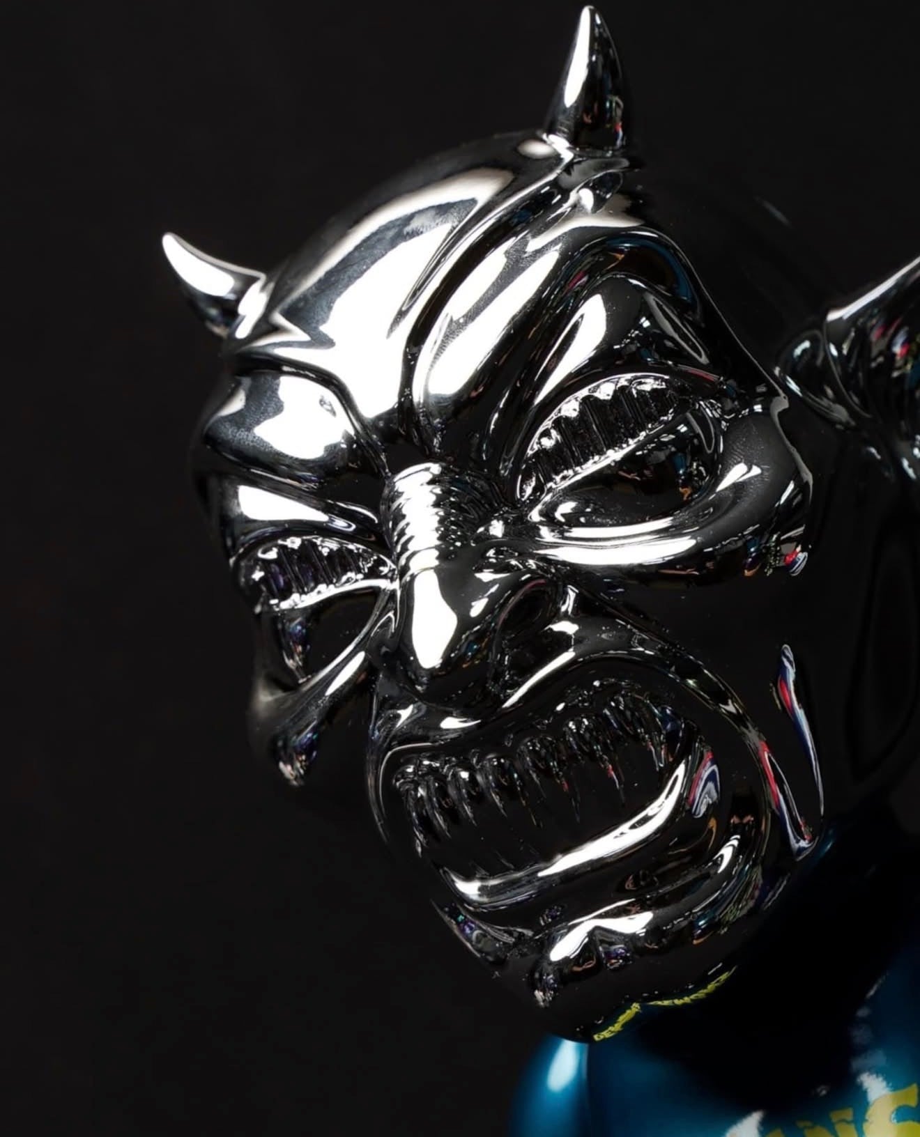 NEO-LASH Chrome Face Edition by MVH: A gleaming demon head sculpture with horns, snarling eyes, and sharp teeth, crafted in soft vinyl, 9.5 tall.