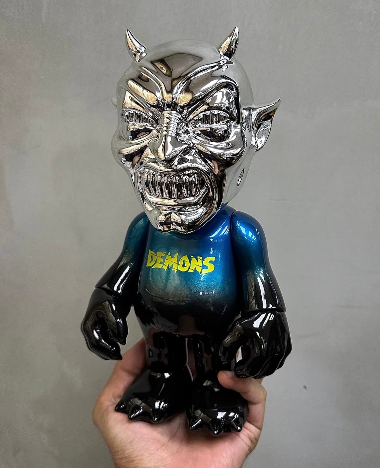 NEO-LASH Chrome Face Edition by MVH features a polished chrome devil head with fangs, horns, and a glossy black-and-teal vinyl body, 9.5 inches tall.