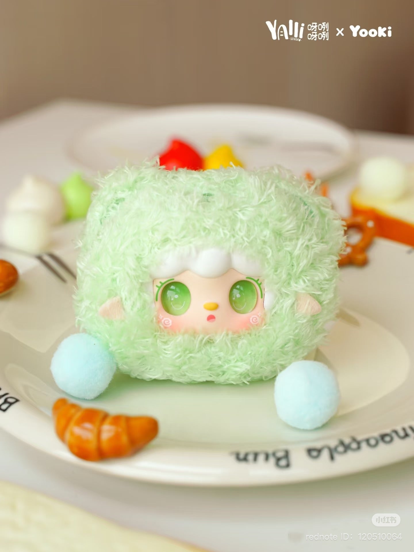Yooki - Little Bear Bun Mini Keychain Plush Blind box on a plate, featuring a stuffed animal face. Preorder ships June 2025.