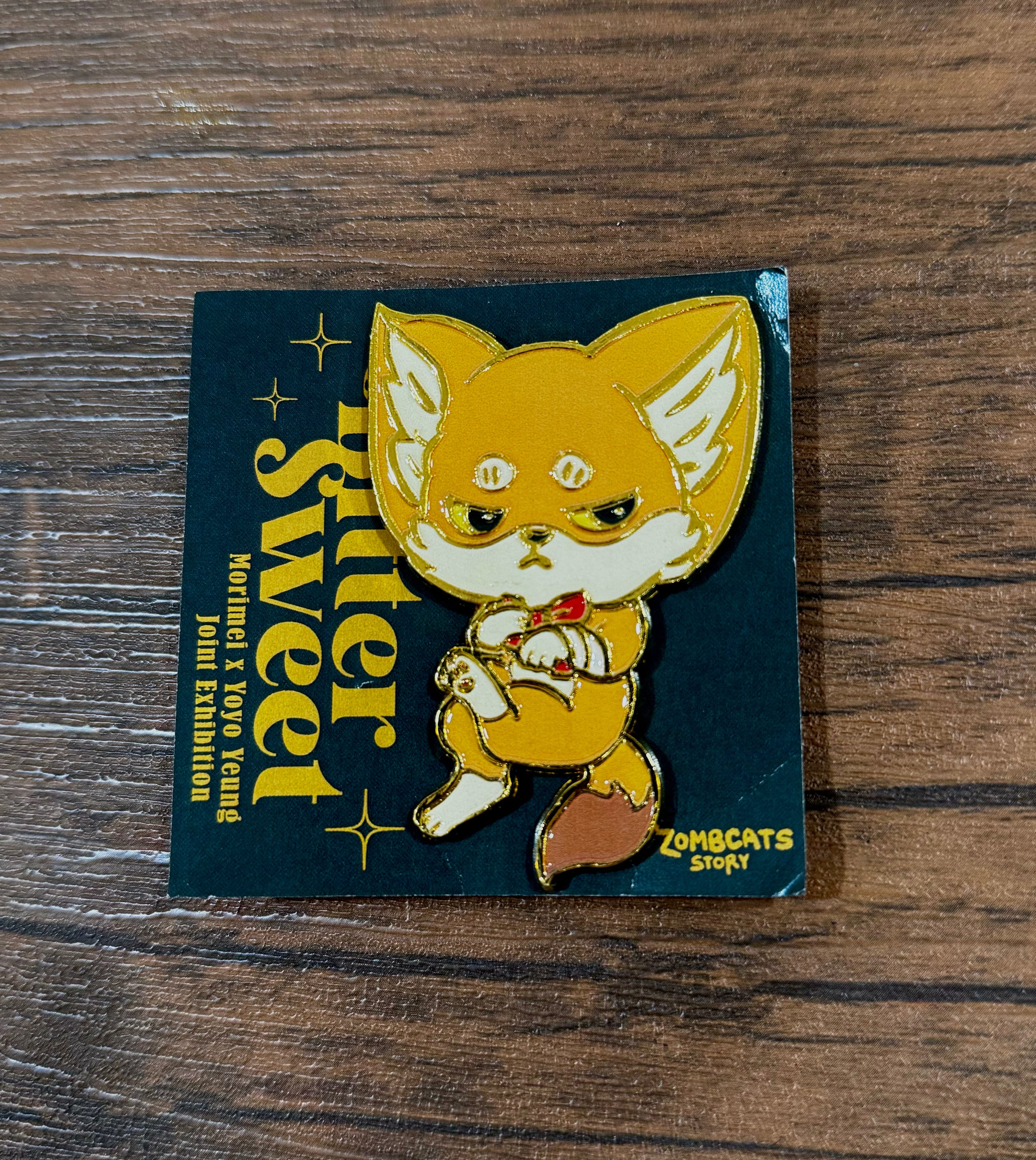 Zombcat x Kenneth Bitter Sweet enamel pin by Morimei x Yoyo Yeung, depicting a cartoon fox on a book cover. Limited edition, 2.5 inches.