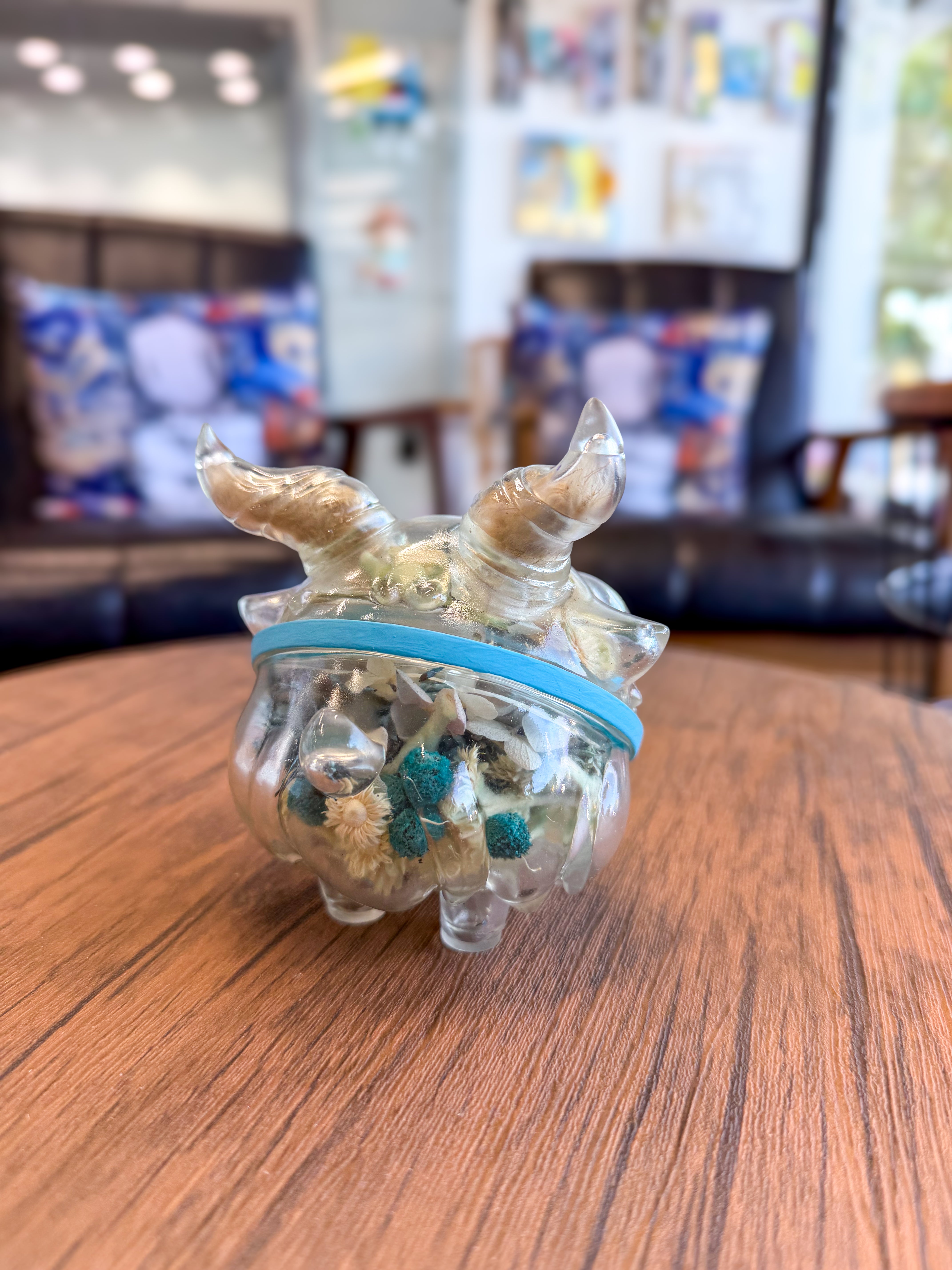 Sweet on the inside Bobbi by Zintears, a 10cm horn-shaped glass jar with dried botanicals, adorned with a blue band, displayed on a wooden tabletop.