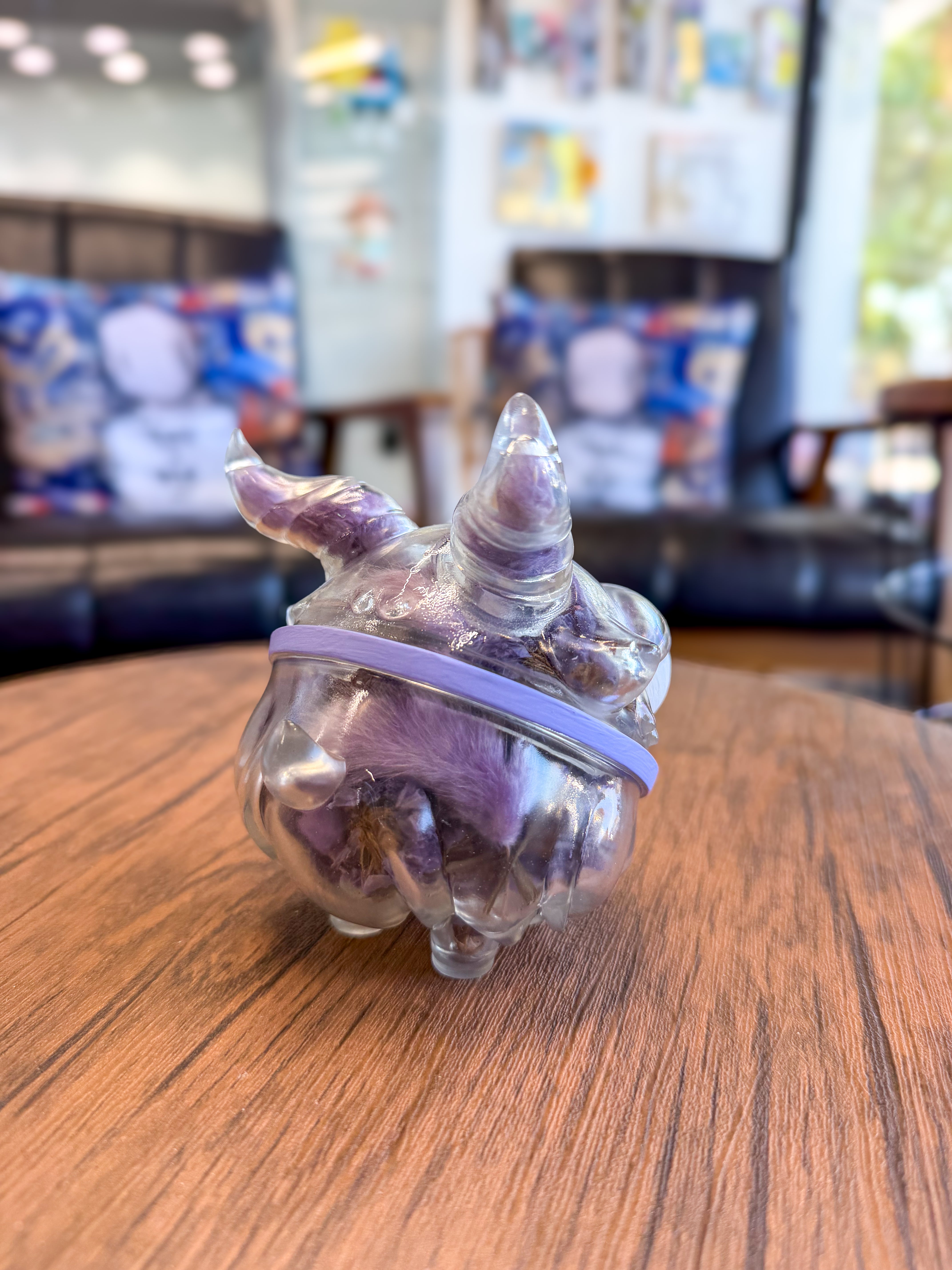 Sweet on the inside Bobbi by Zintears, a translucent 10cm vinyl figurine with horns and lavender band, sits on a table.
