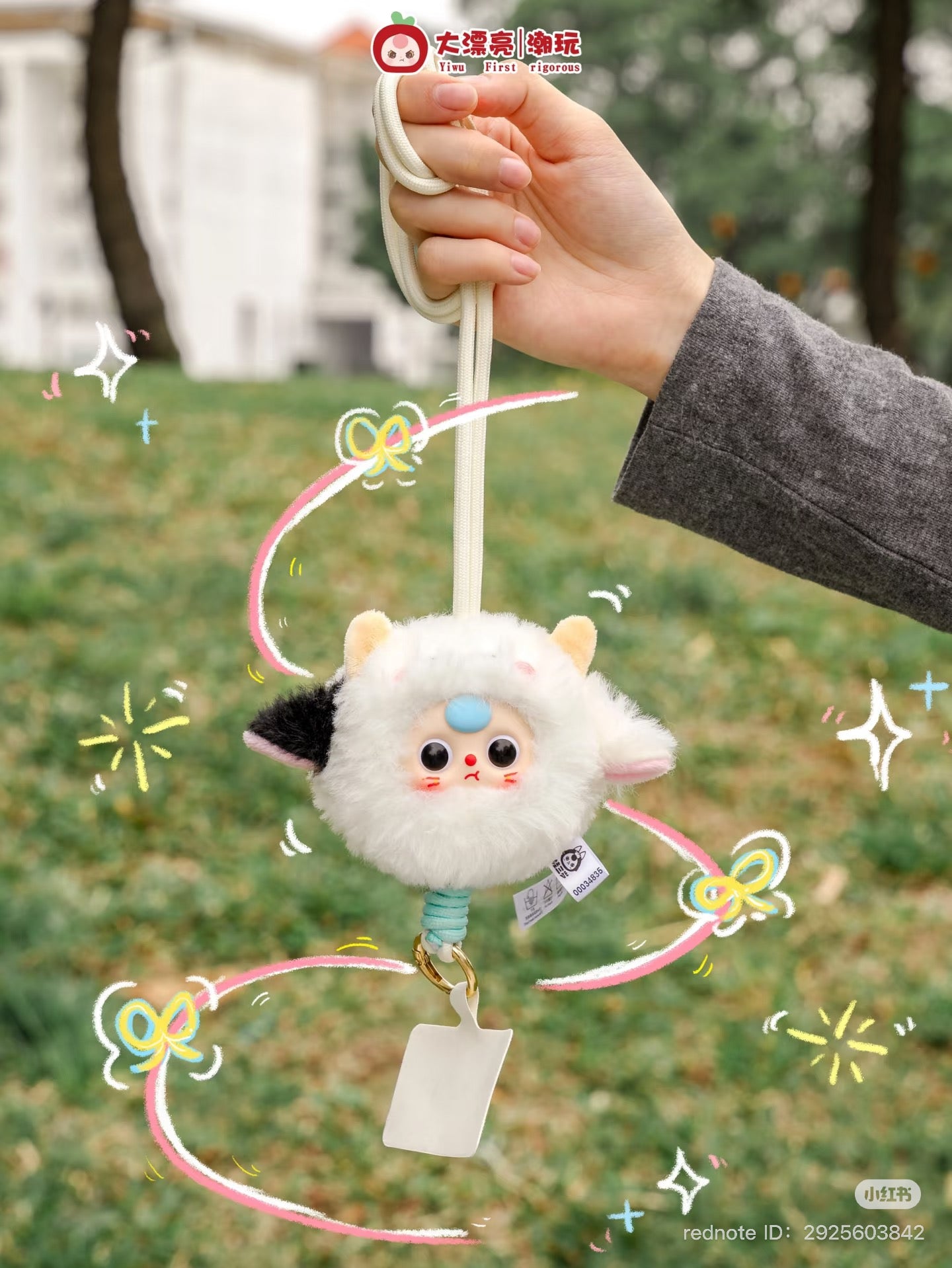 Baby Three Mobile phone strap Plush Blind Box preorder, featuring a close-up of a cartoon toy held by a hand, set against an outdoor grass backdrop.
