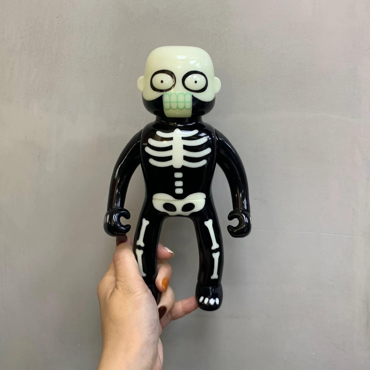 Mr. Nobodies vinyl toy, a stylized skeleton figure with white bone graphics, held in hand, designed by Lick Palik for preorder.