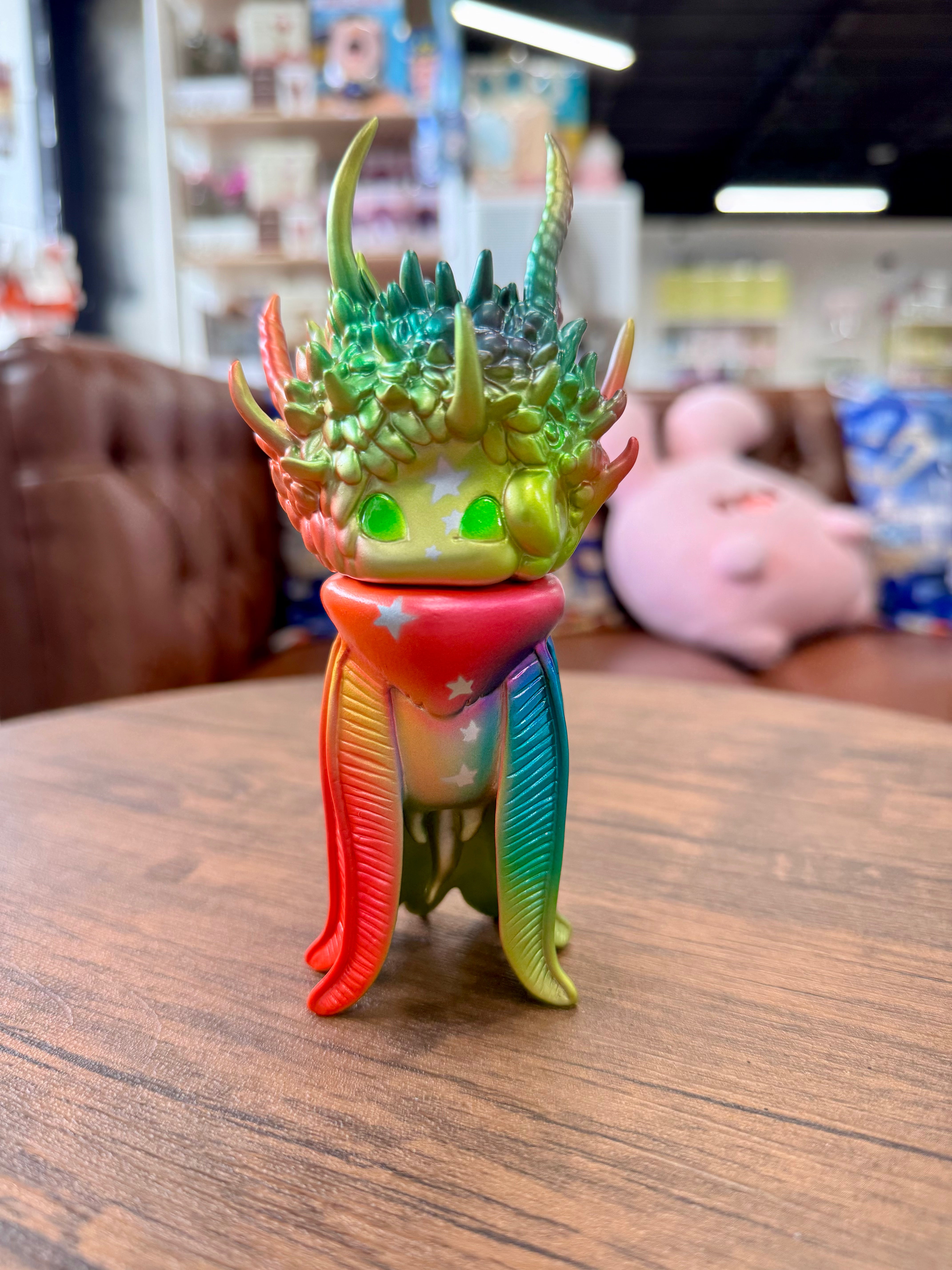 Genie Metal Gradation by YASU, a Japanese Sofubi art toy, displayed on a table, showcasing intricate design details.