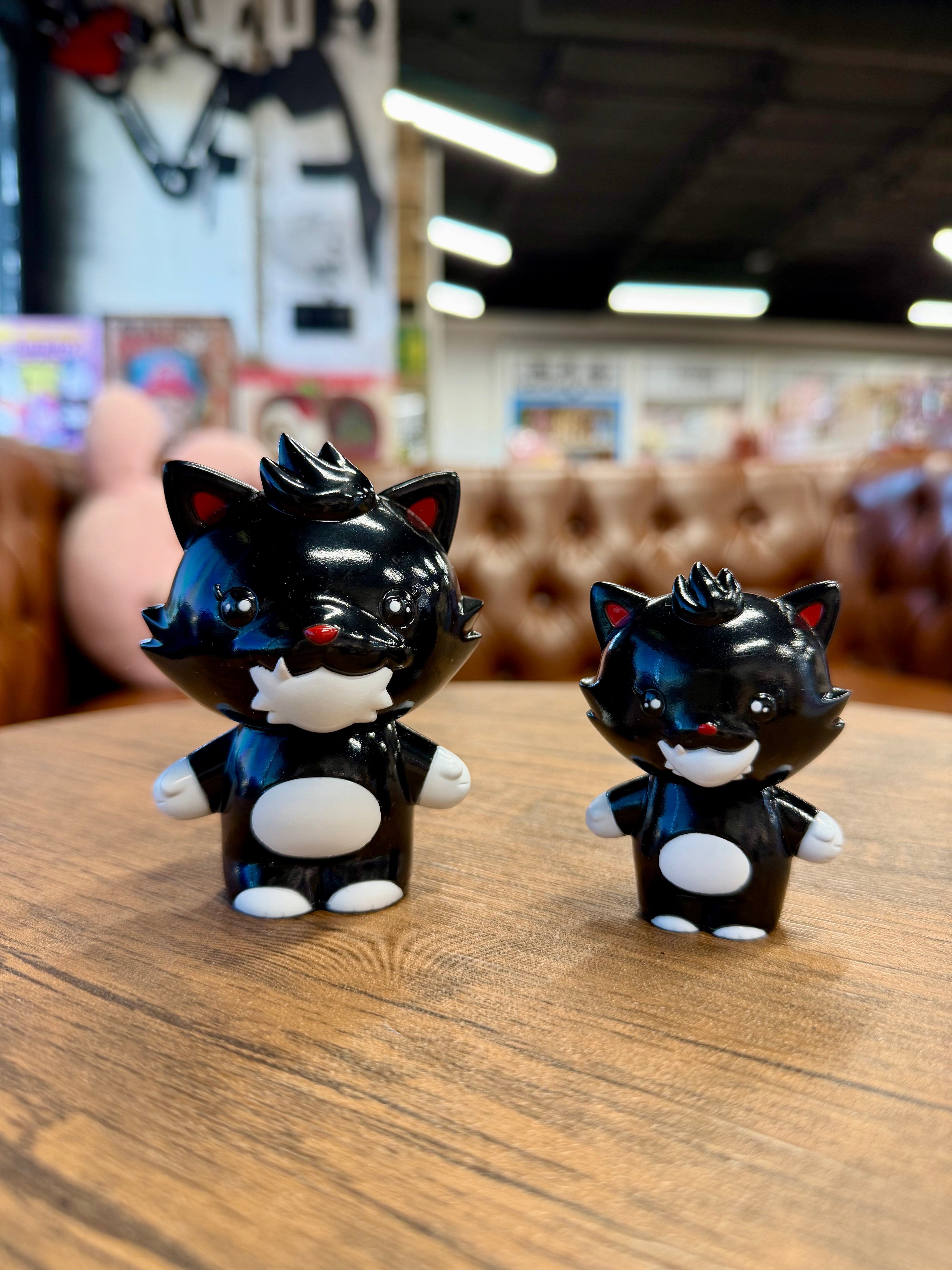 Grandpa Sofubi - OG: Two black cartoon-style cat figurines, sculpted by P.P.PUDDING, on a tabletop, showcasing playful character design by In Prime We Trust.